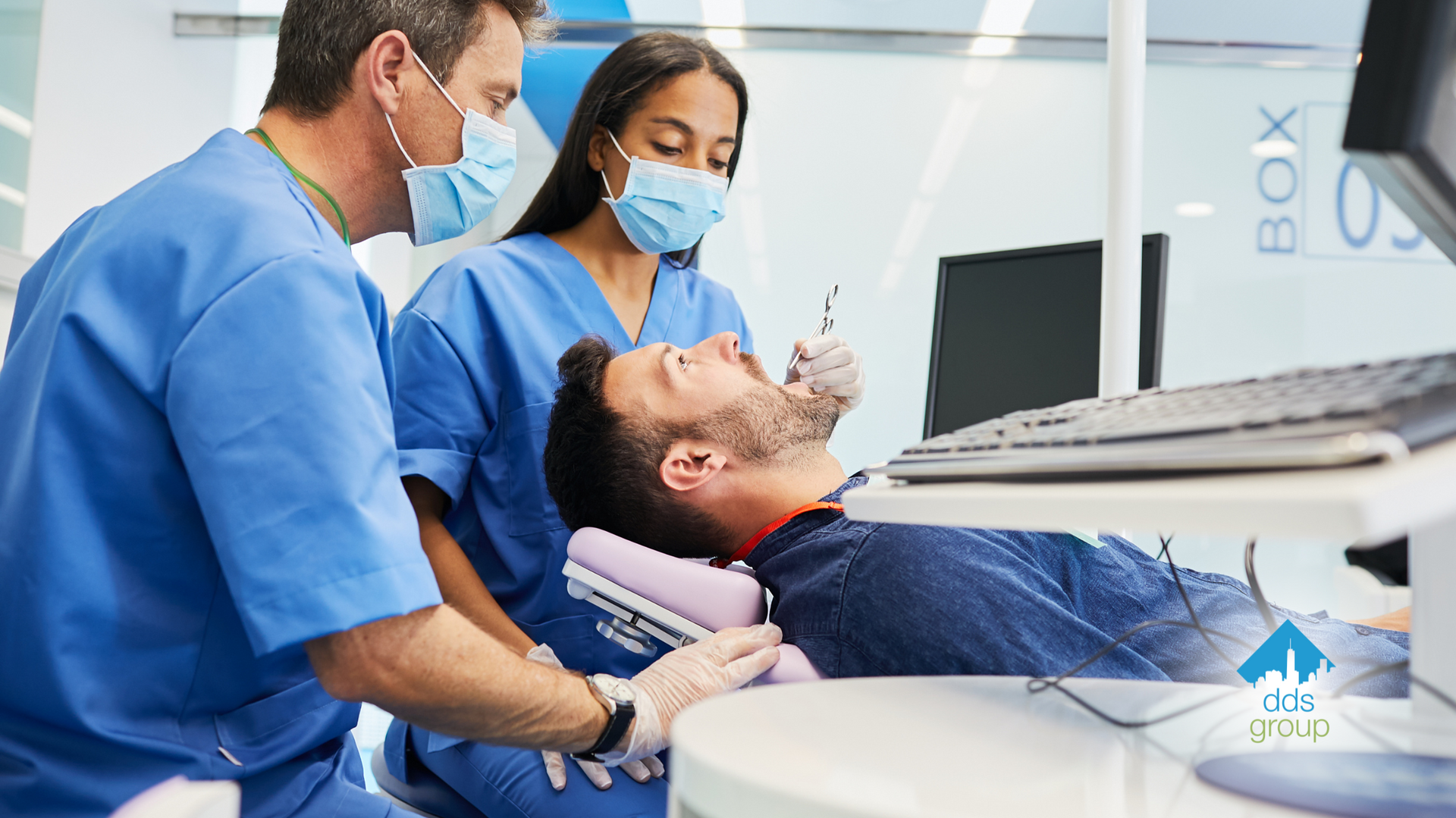 A man is getting his teeth examined by two dentists in a dental office.