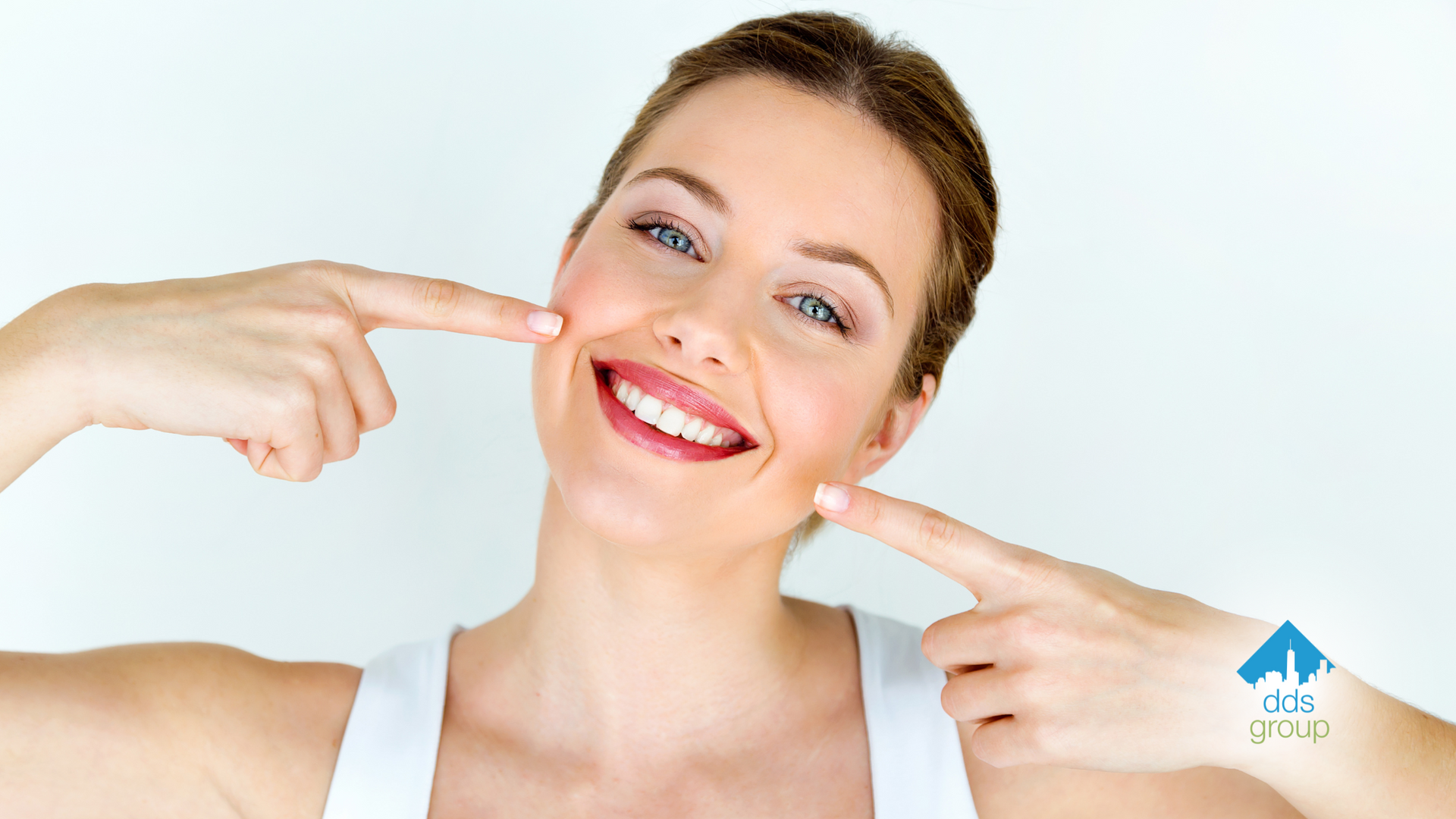 A woman is smiling and pointing at her teeth.