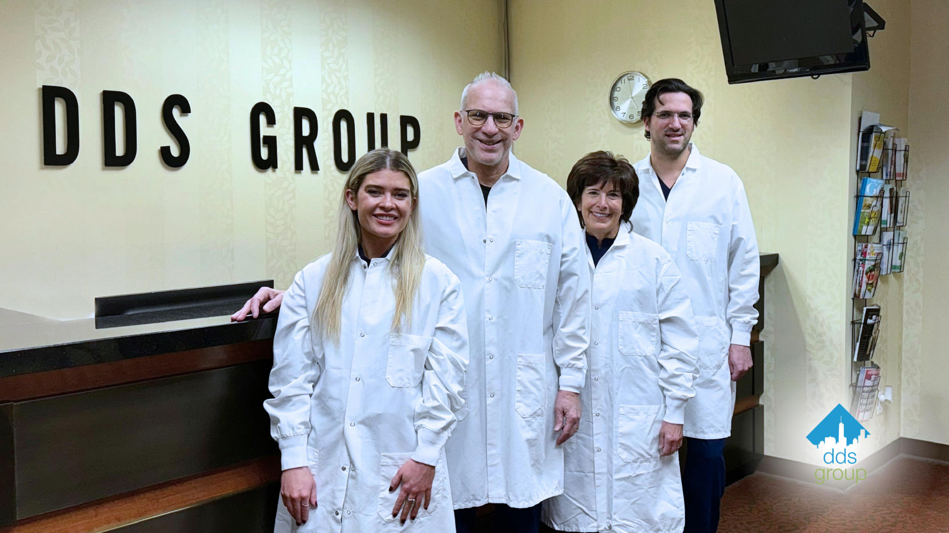 A group of doctors are posing for a picture in front of a sign that says dds group.