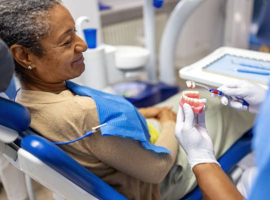 Dentist holding teeth model, smiling in a dental office.