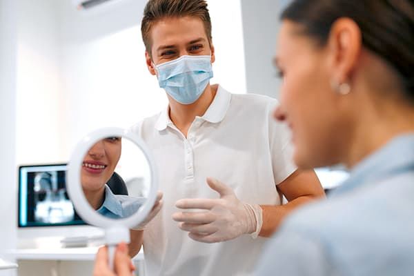 Dentist matching a shade guide to a patient's teeth during a dental procedure.