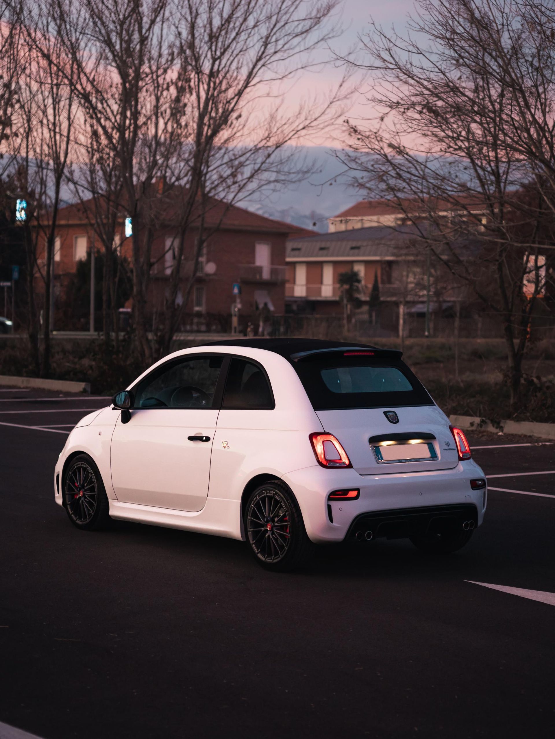Un'auto bianca percorre una strada con alberi sullo sfondo.