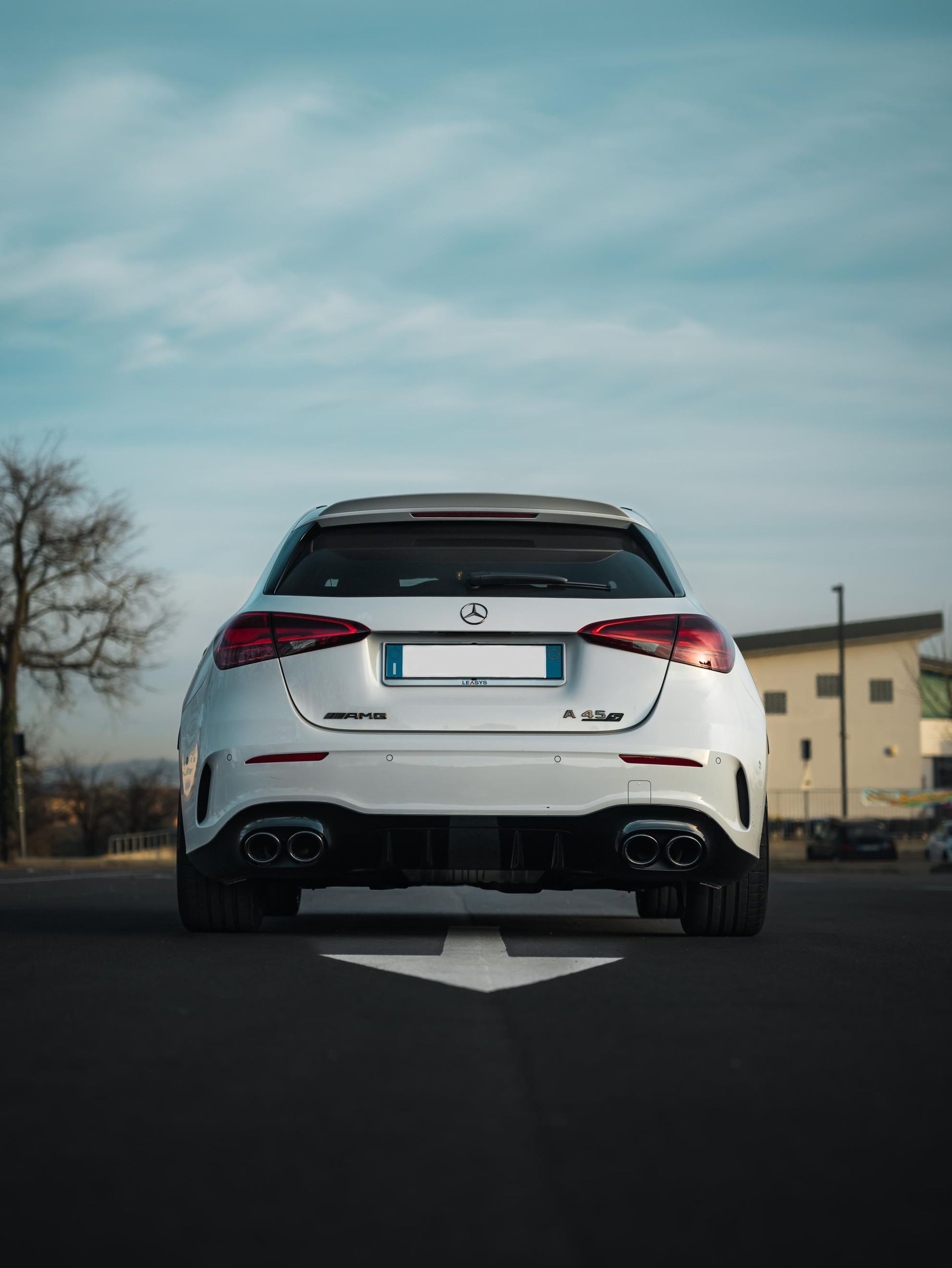 Un'auto bianca è parcheggiata in un parcheggio con una freccia che punta verso destra.