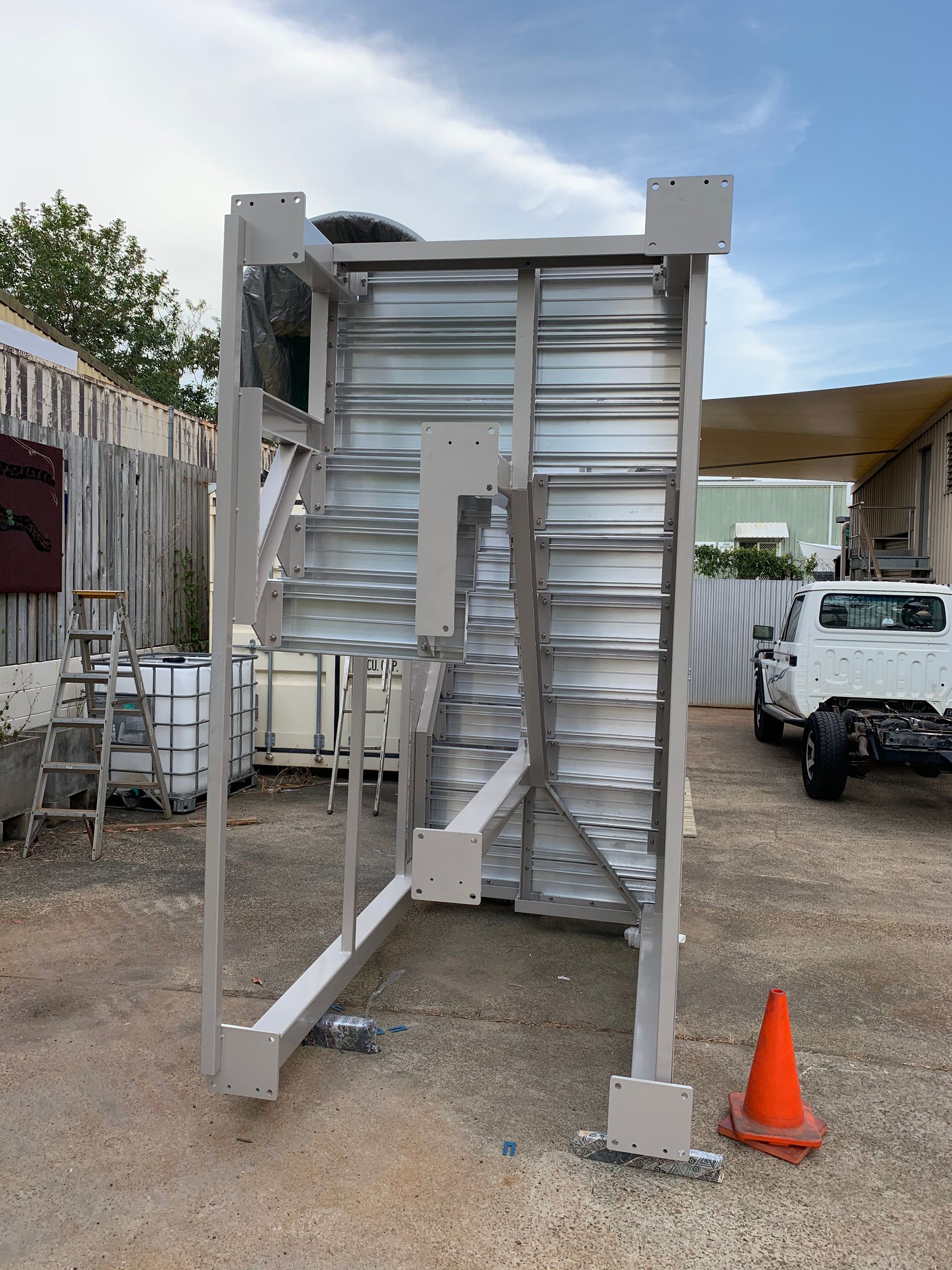 A white truck is parked in front of a metal structure in a parking lot. — Keystone Engineering Sheet Metal Industries in Noosaville, QLD