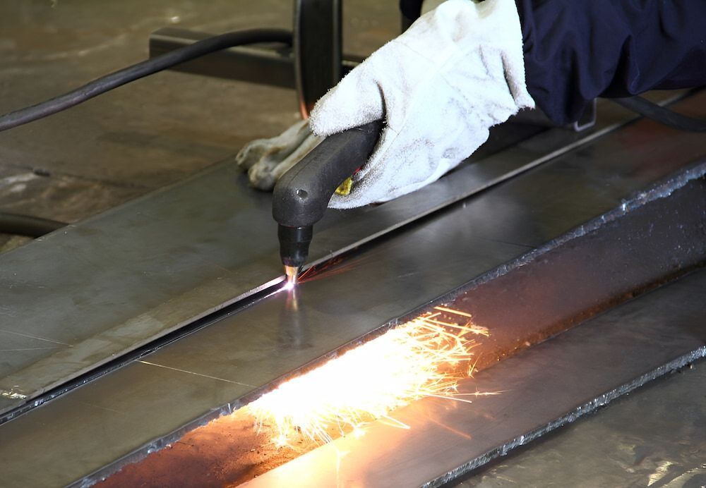 A Person Is Cutting A Piece Of Metal With A Torch — Keystone Engineering Sheet Metal Industries in Noosaville, QLD