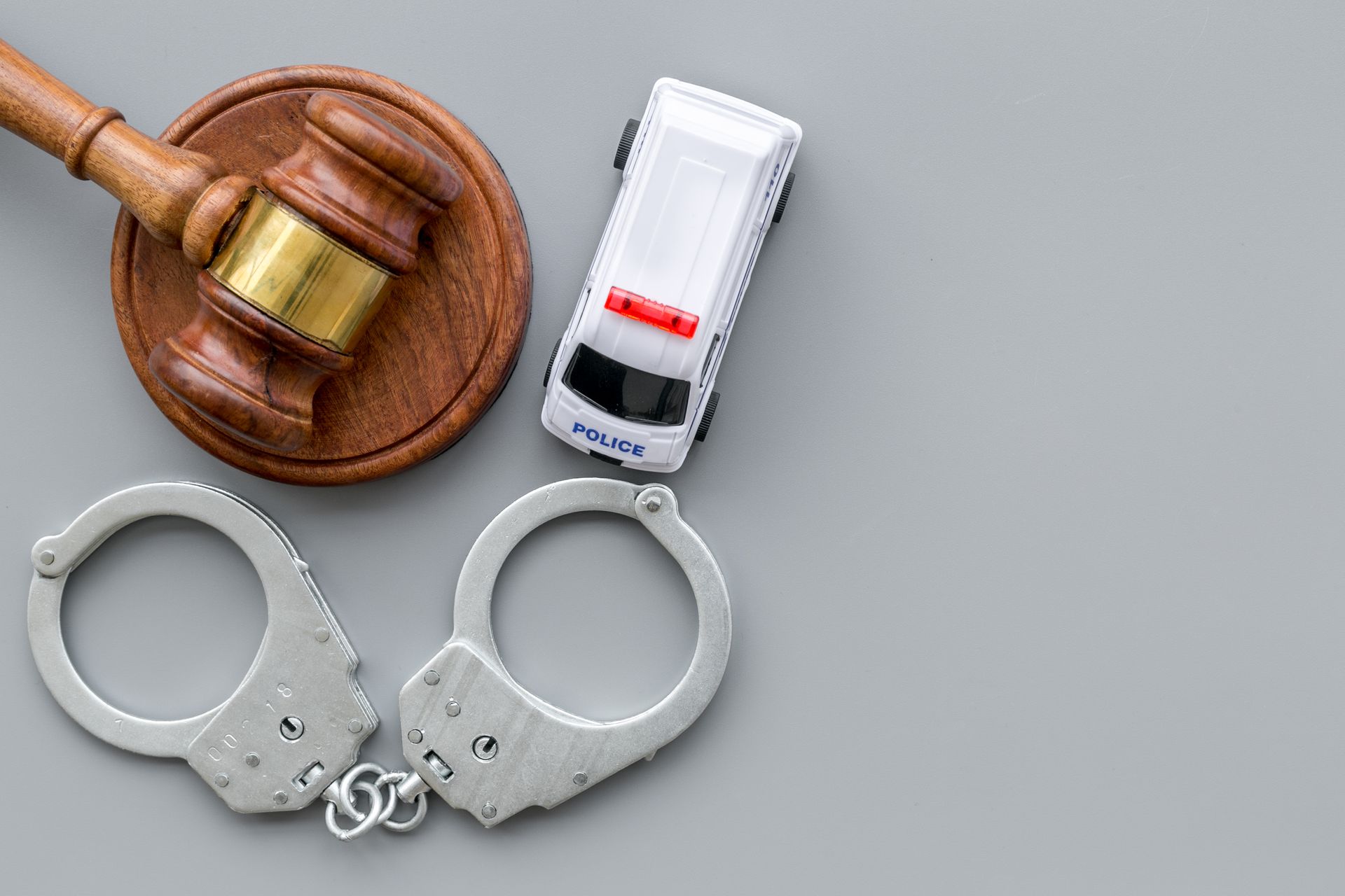 A pair of handcuffs , a judge 's gavel , and a toy police car on a table.