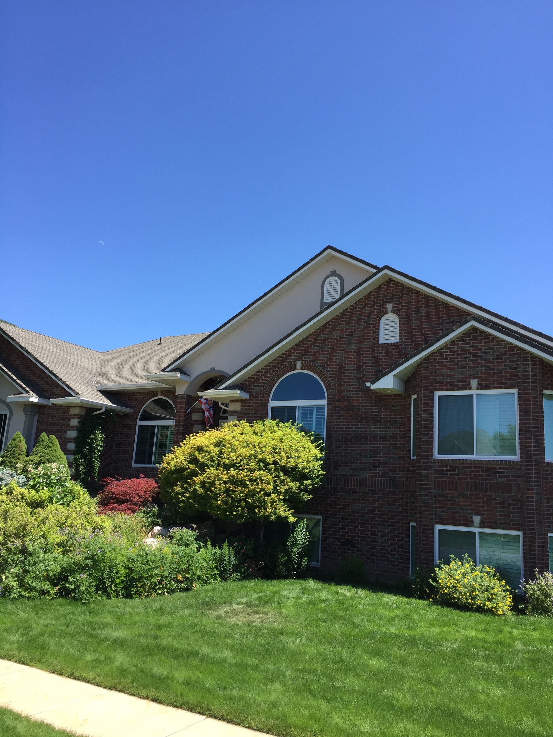 Brick house with a landscaped yard under a blue sky.