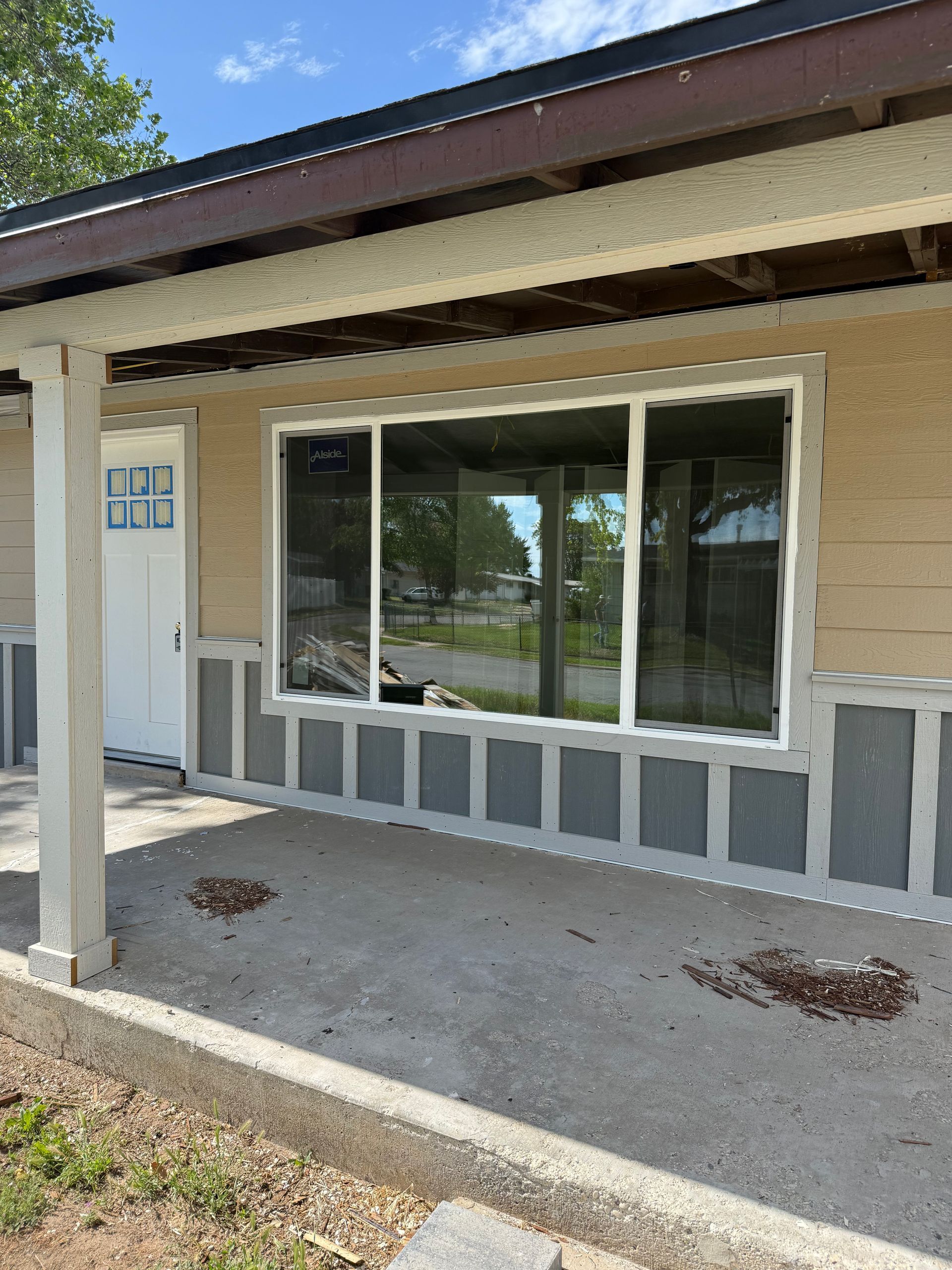 Exterior view of a house with white windows and door, stucco walls, and a concrete porch.