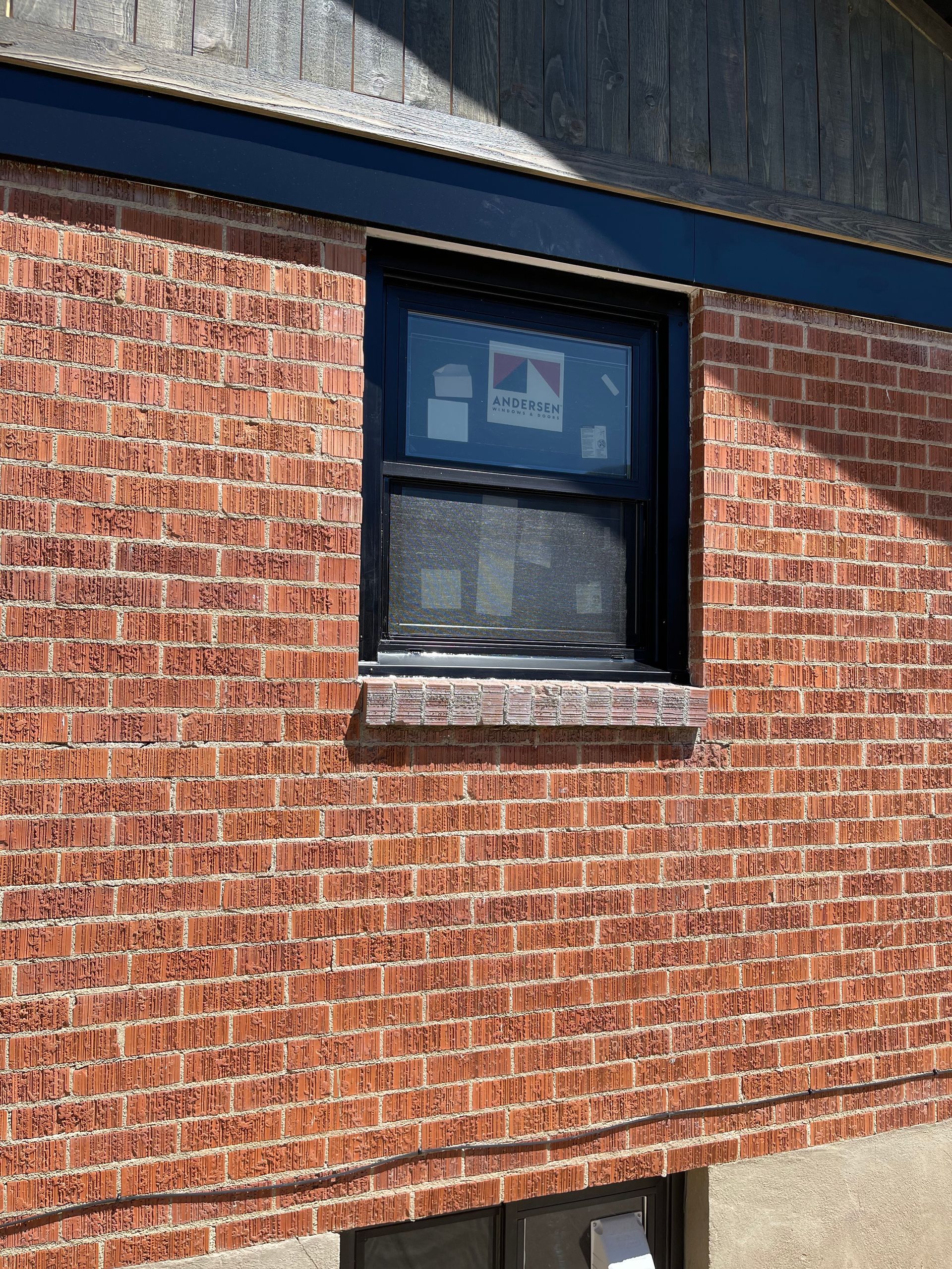 Red brick building with a black framed window.