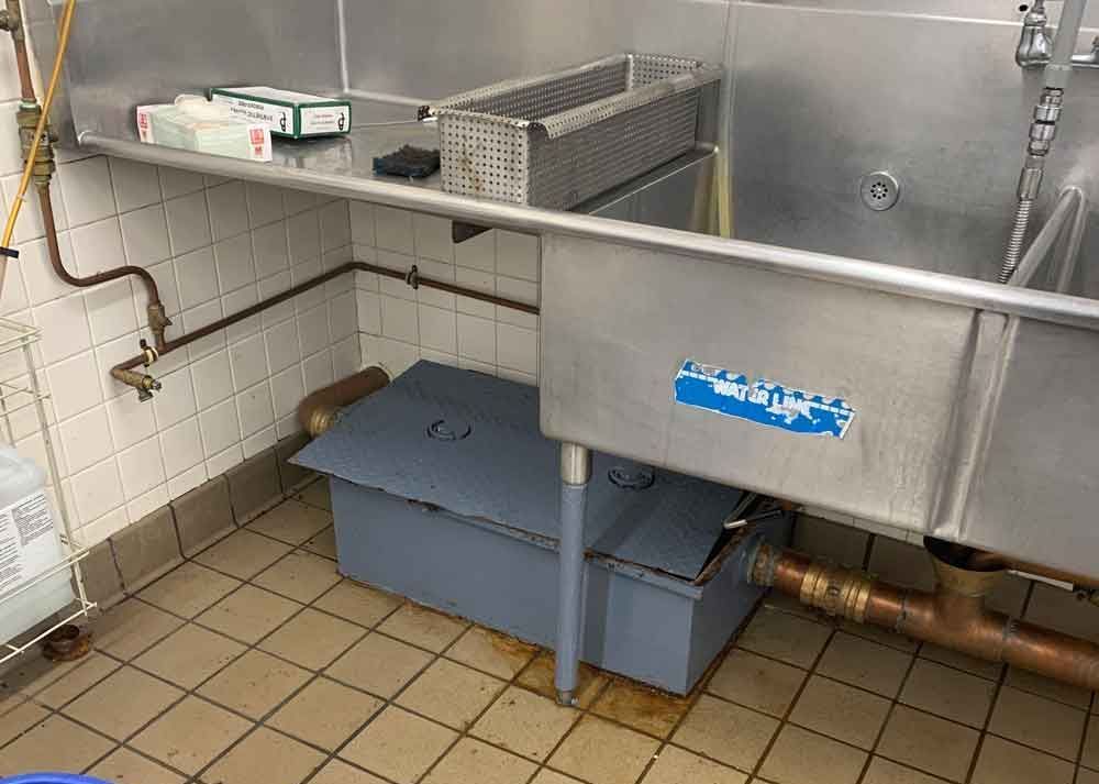 A stainless steel sink in a kitchen with a blue box underneath it.