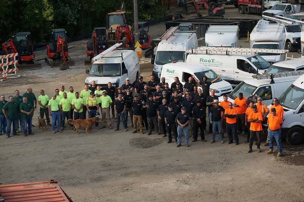 A large group of people are posing for a picture in front of a bunch of trucks.