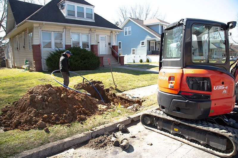 A man is digging a hole in the ground in front of a house.