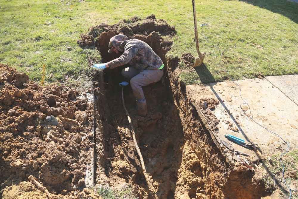 A man is digging a hole in the ground with a shovel