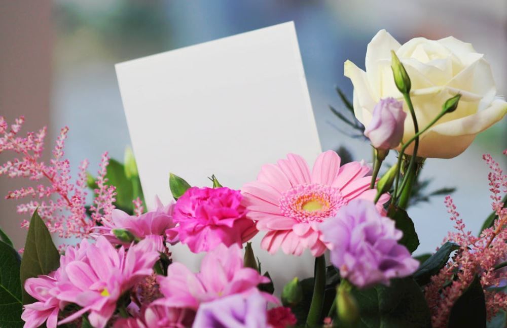 Pink gerbera and white rose bouquet with empty note card for a personal tribute, cremation services 