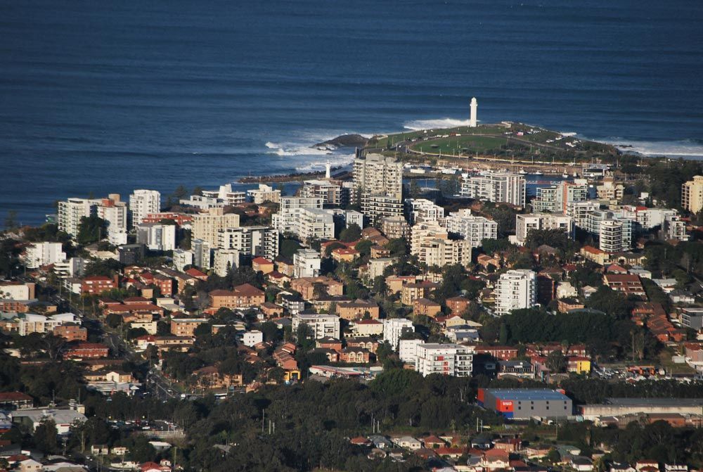 An Aerial View Of A City With A Lighthouse In The Distance — B Smart Building & Design In Balgownie, NSW