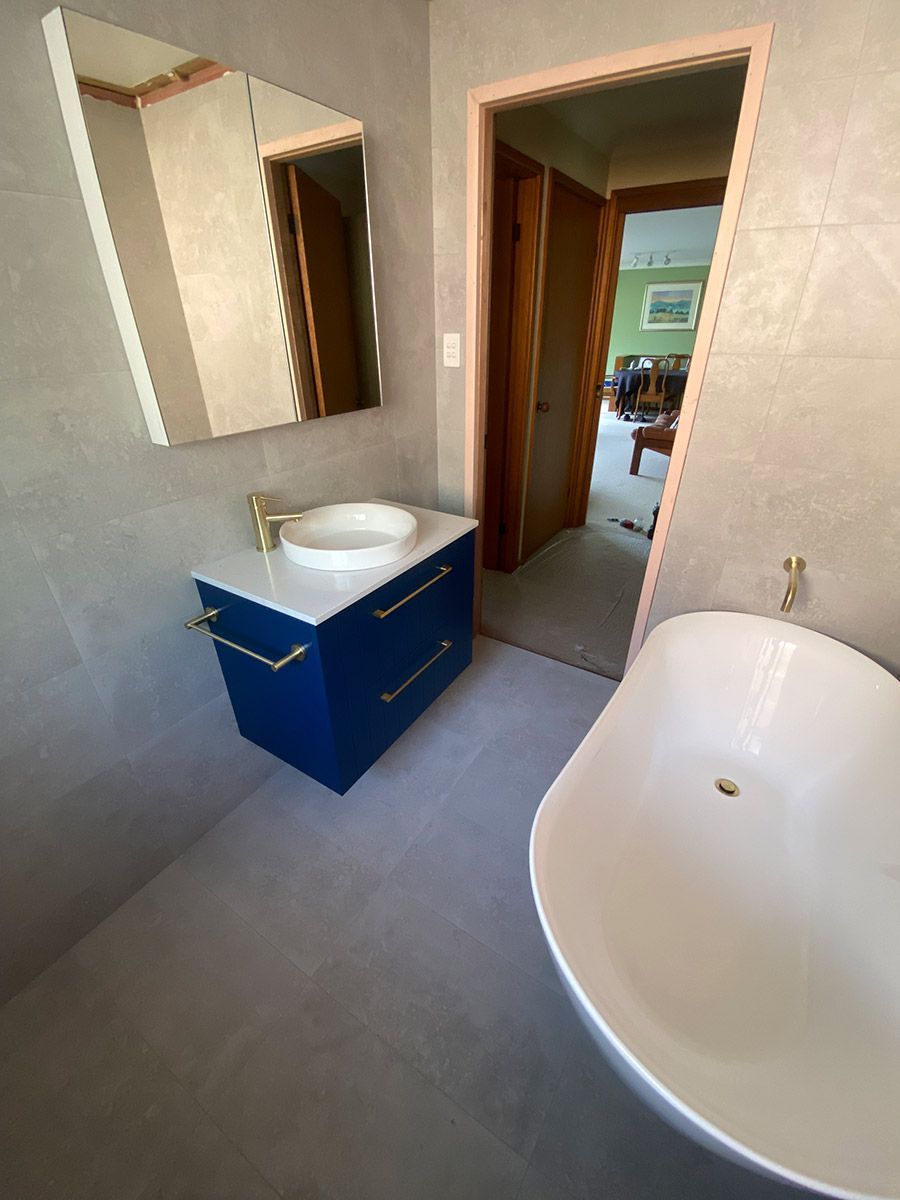A Bathroom With A Bathtub , Sink And Mirror — B Smart Building & Design In Gerringong, NSW