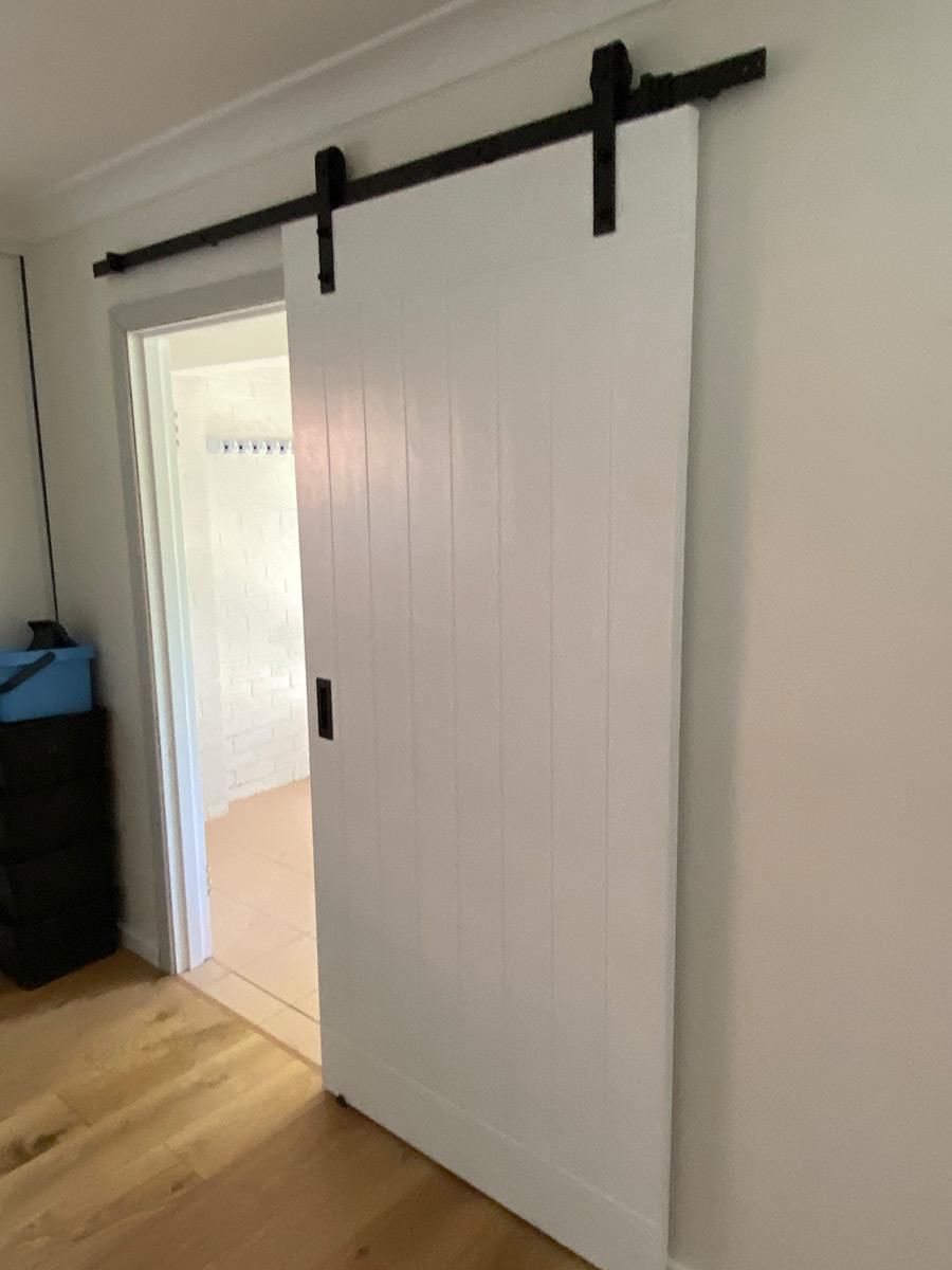 A White Sliding Barn Door Is Hanging On A White Wall In A Room — B Smart Building & Design In Gerringong, NSW