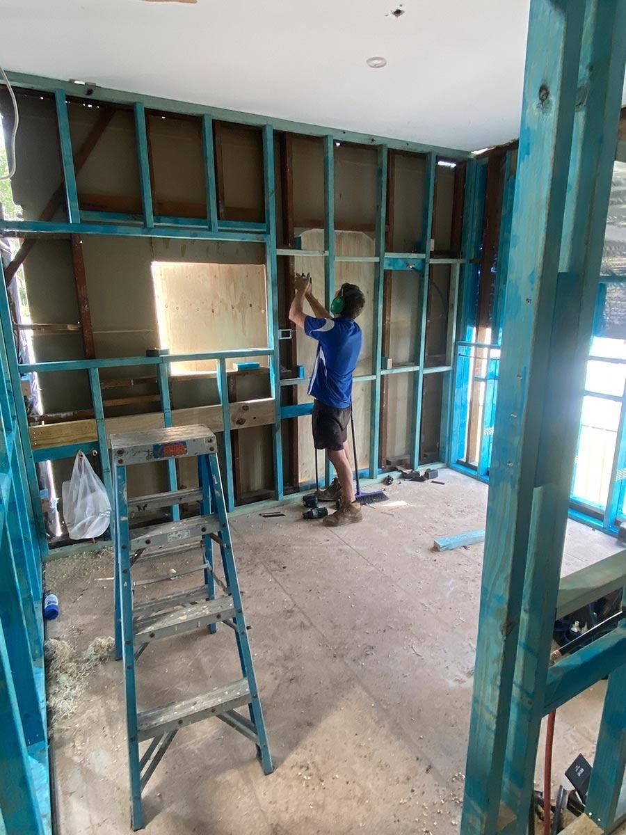A Man Is Working On A Wall In A Room With A Ladder — B Smart Building & Design In Shellharbour, NSW