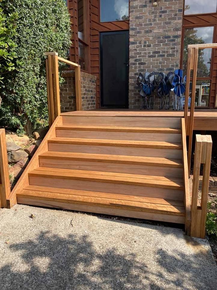 A Wooden Deck With Stairs Leading And A Brick Wall In The Background — B Smart Building & Design In Shellharbour, NSW