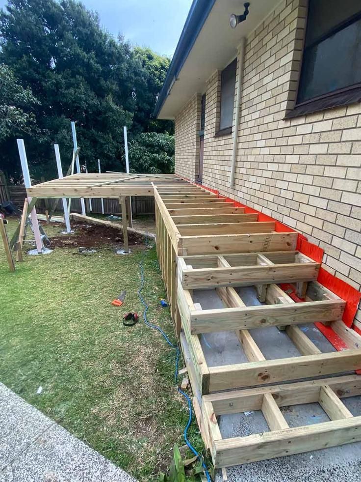 A Wooden Deck Is Being Built On The Side Of A Brick House— B Smart Building & Design In Shellharbour, NSW