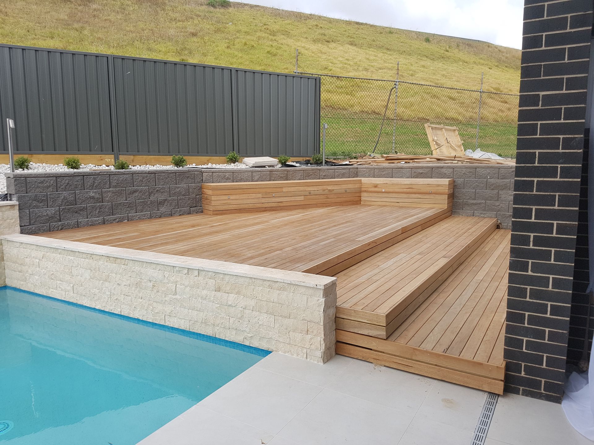A House Is Sitting On Top Of A Hill Next To A Fence — B Smart Building & Design In Shellharbour, NSW