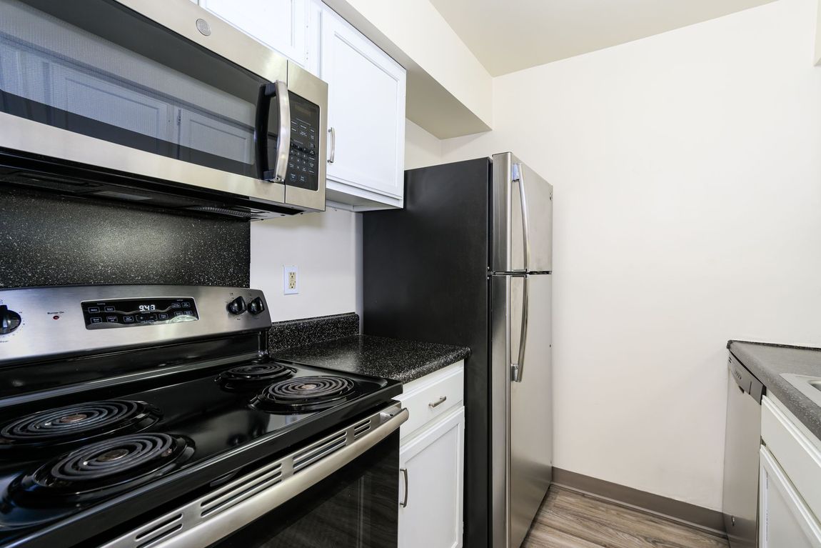 A kitchen with a stove , refrigerator , microwave and dishwasher.