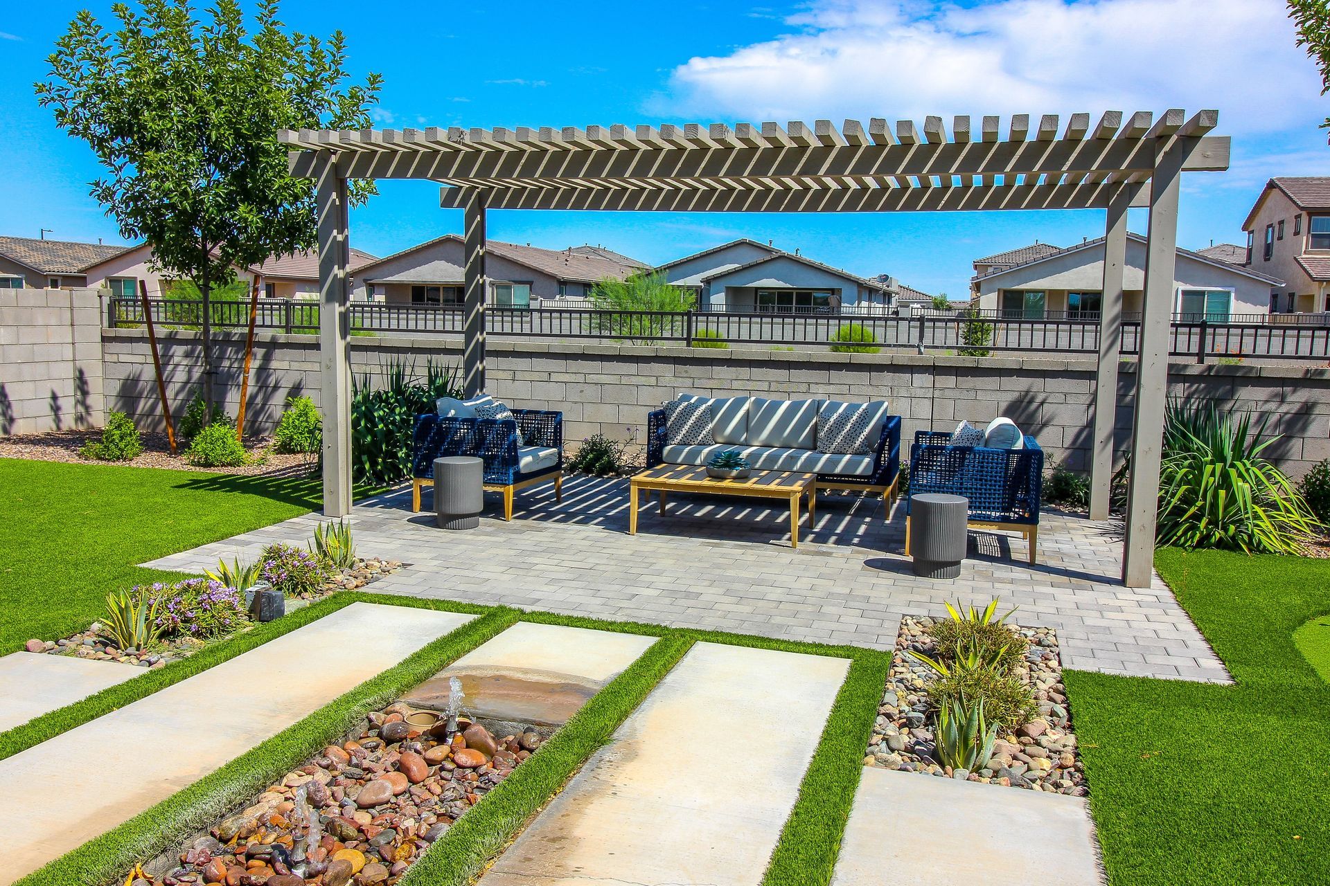 Backyard patio with pergola, outdoor seating, and stepping stones on green lawn