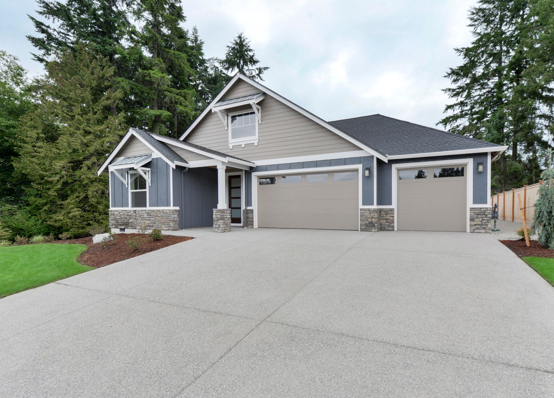 A house with two garage doors and a concrete driveway