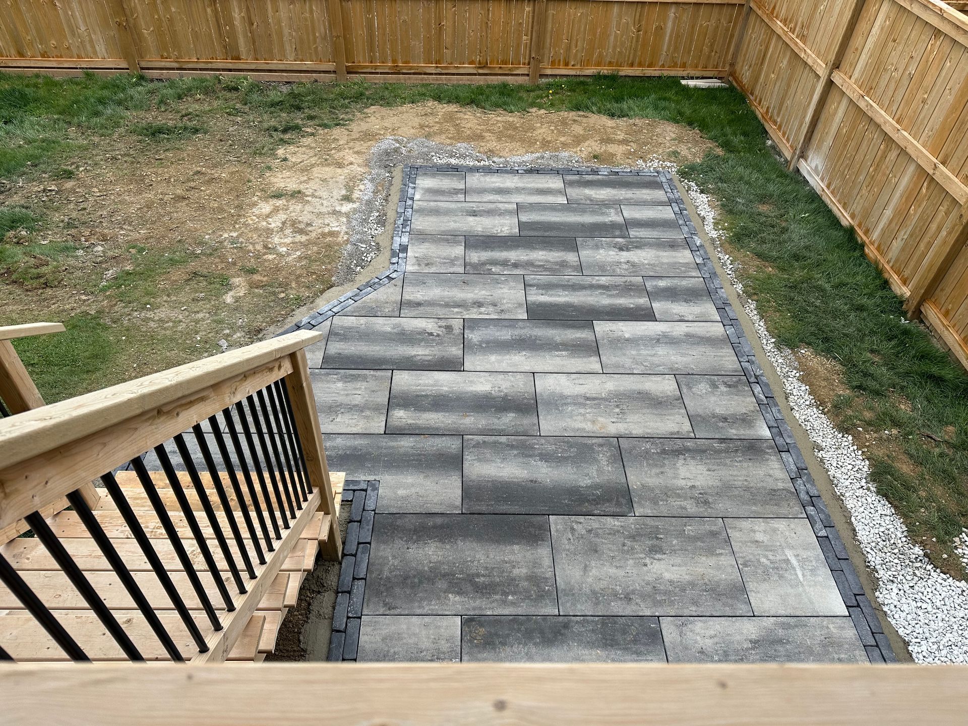 A patio with stairs leading up to it and a wooden fence in the background.