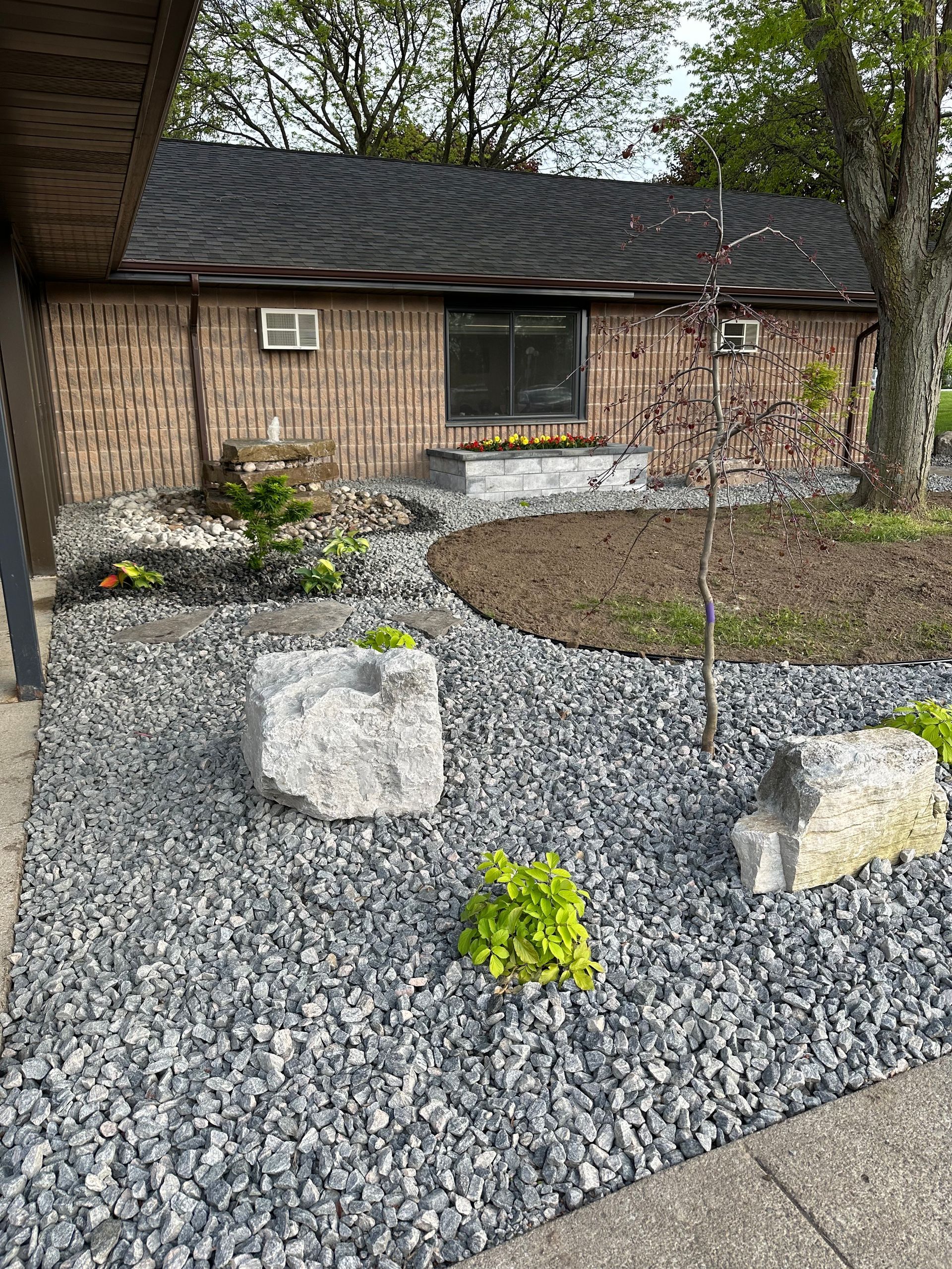 A garden with rocks and plants in front of a house.