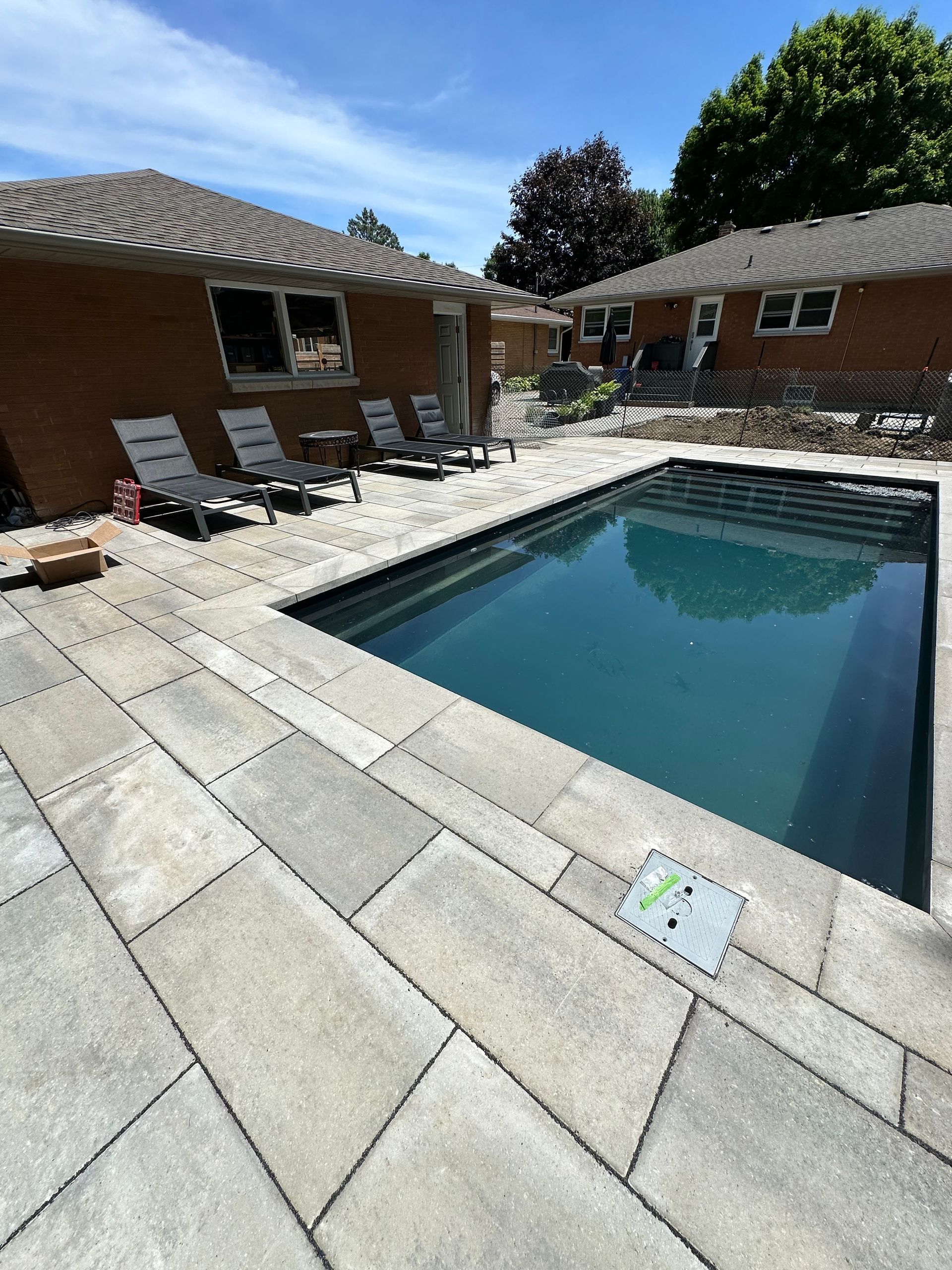 A large swimming pool is in the backyard of a house