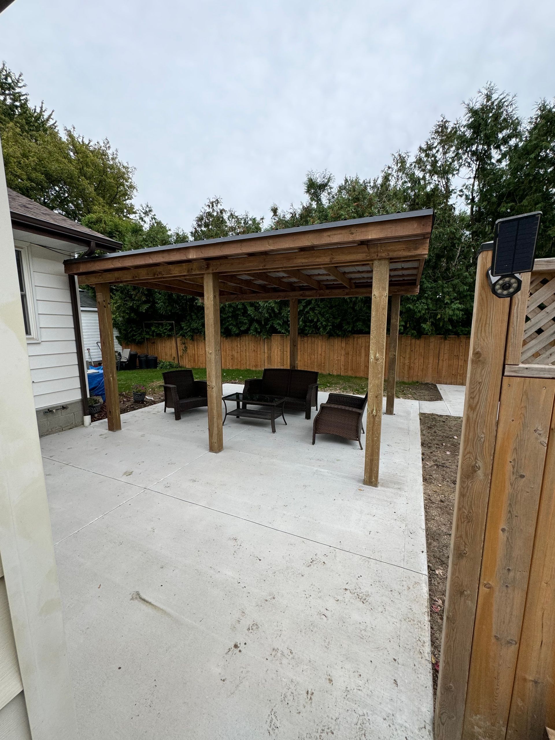 A backyard with a wooden pergola and patio furniture.
