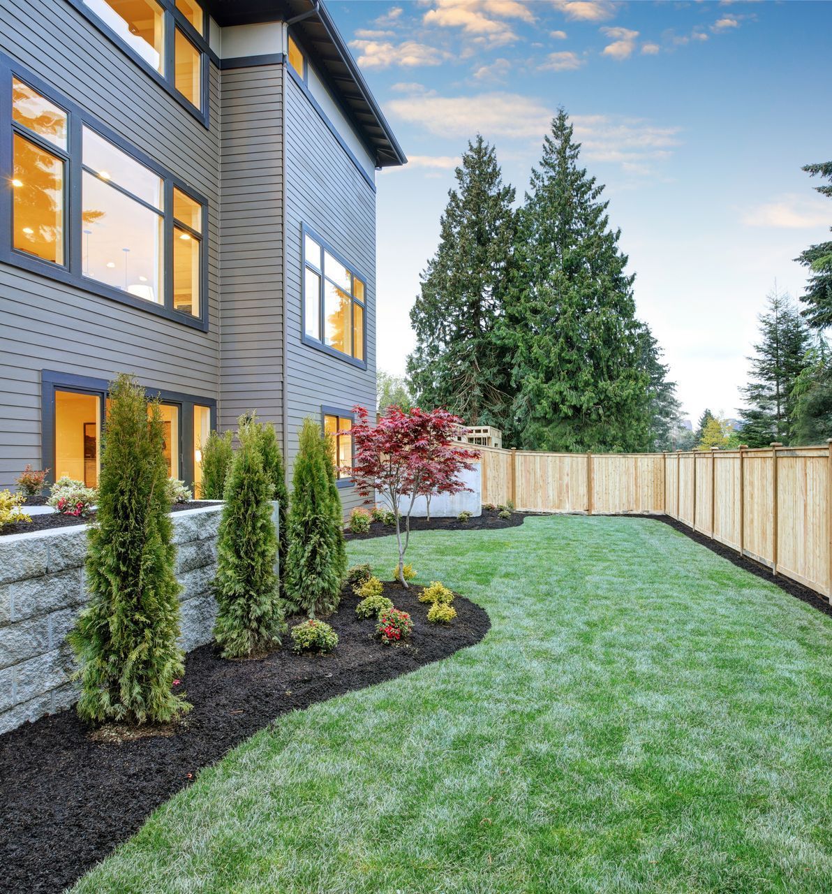 A large house with a large lawn and a wooden fence
