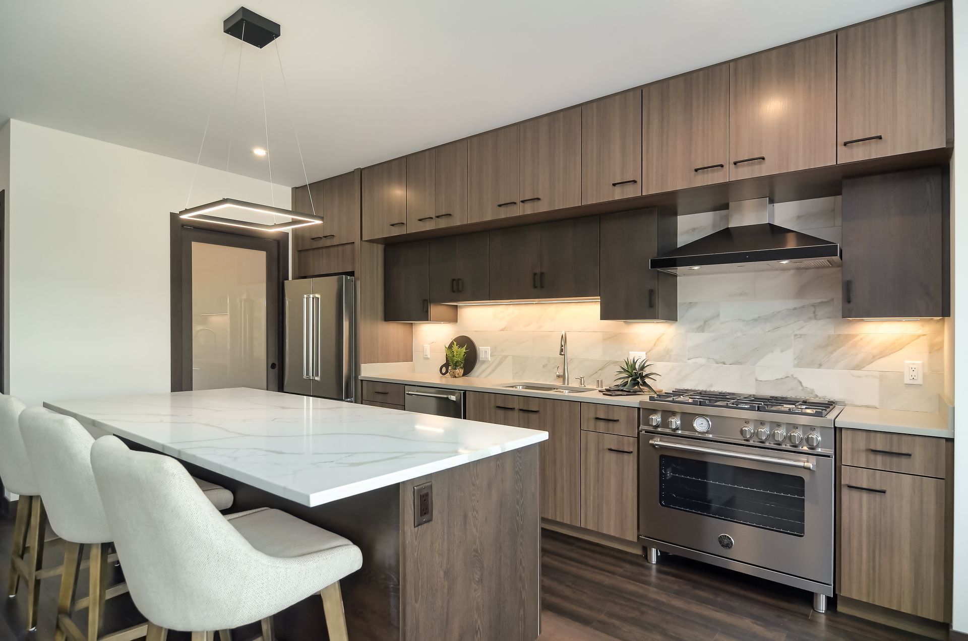 Modern kitchen with white island, stainless steel appliances, and wood cabinets.