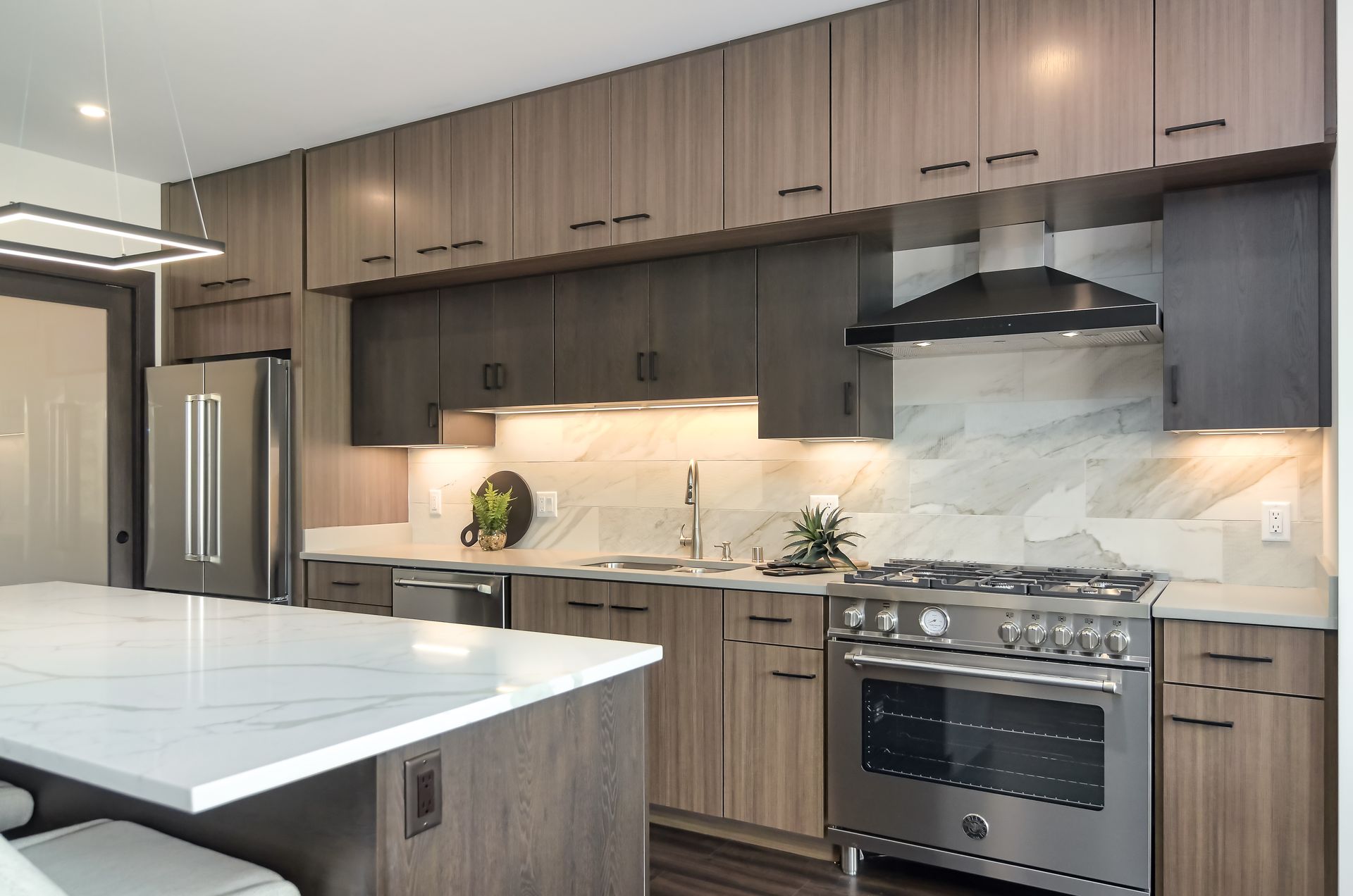 Modern kitchen with wood cabinets, marble countertops, stainless steel appliances, and a large island.