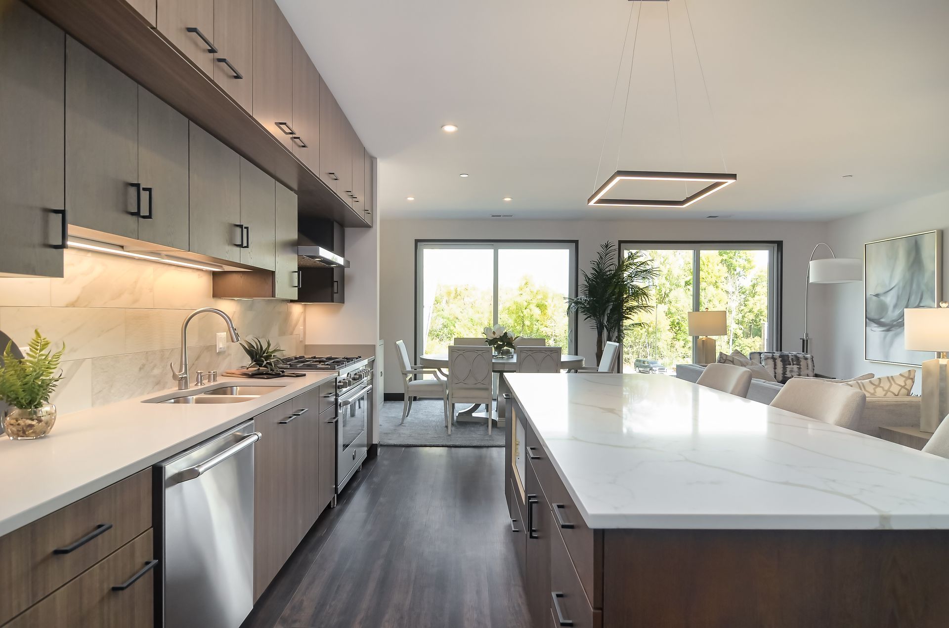 Modern kitchen with gray cabinets, marble countertops, stainless steel appliances, and a large island.