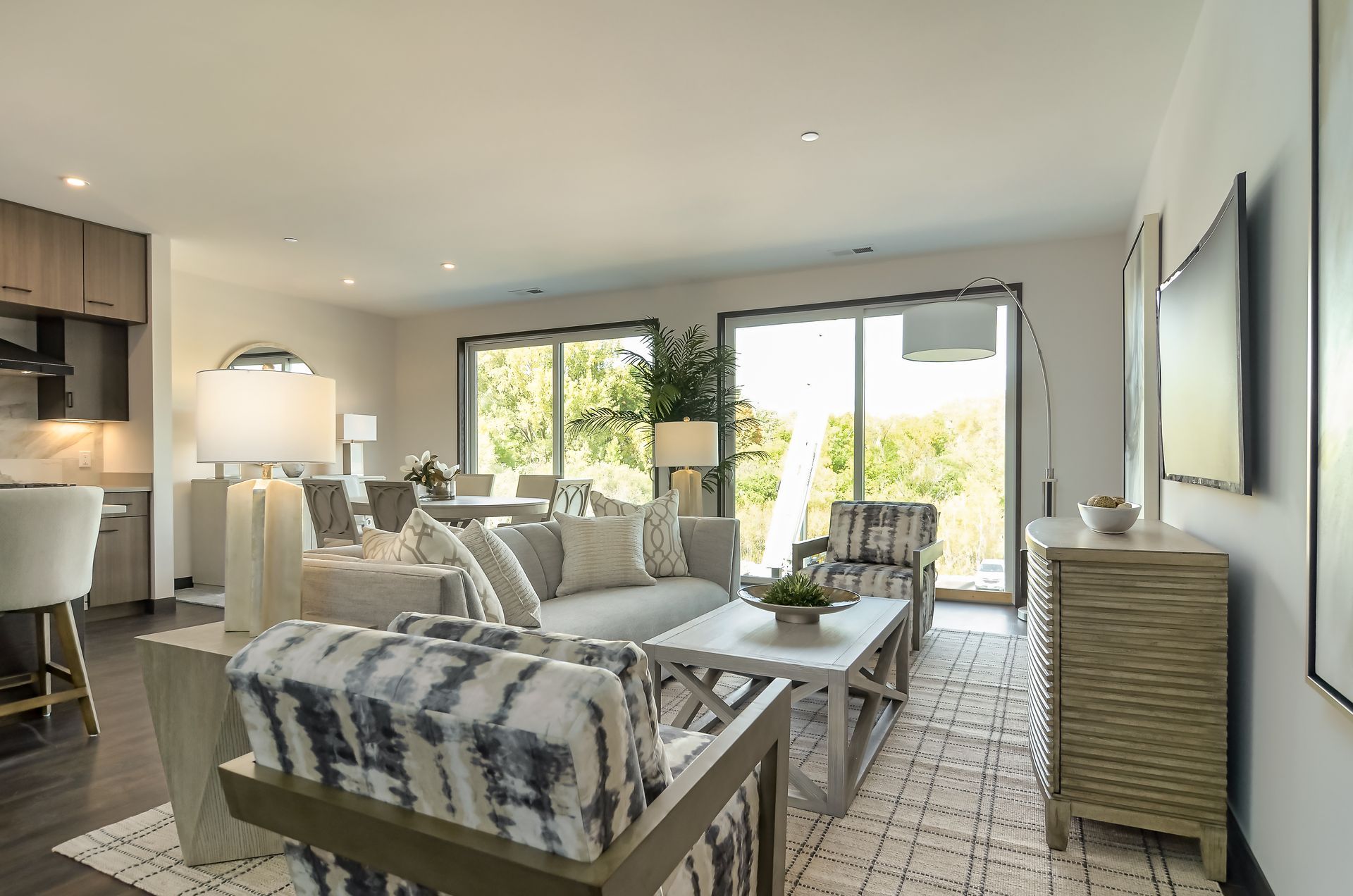 Living room with gray sofa, patterned armchairs, rug, and sliding glass doors.