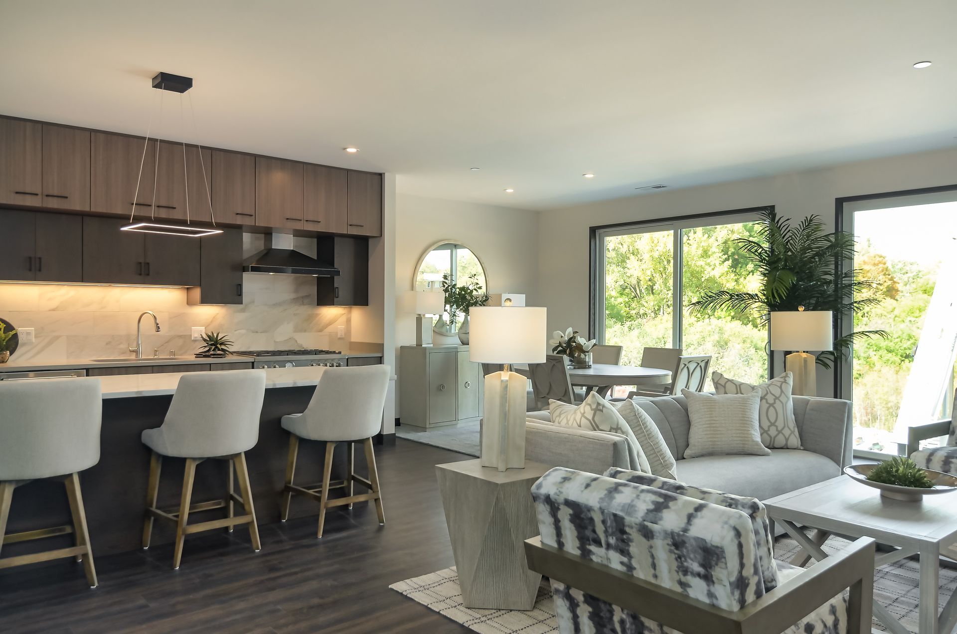 Open-concept living space with kitchen and living room. Neutral colors, natural light, and modern decor.