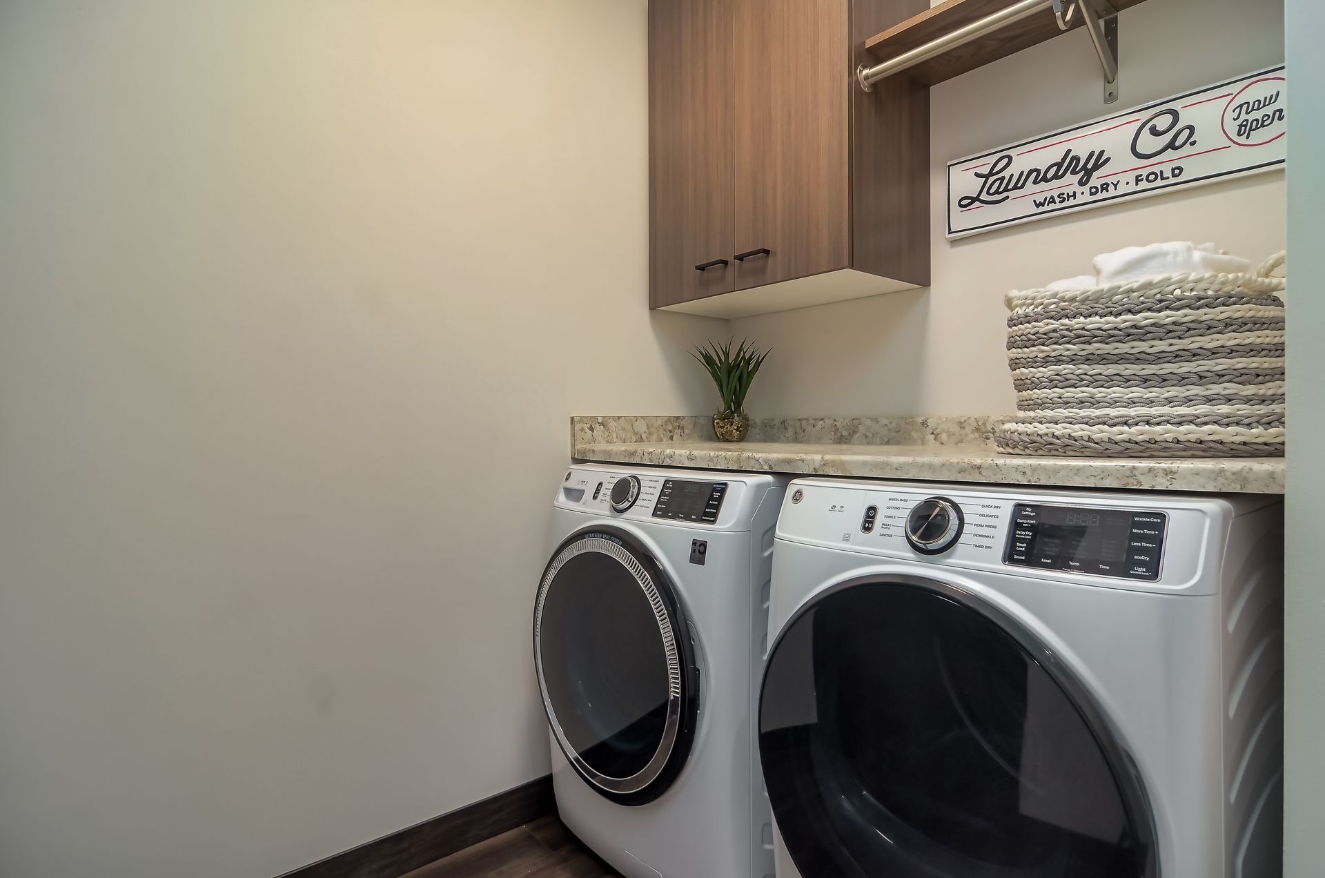 Laundry room with a washing machine, dryer, storage cabinet, and laundry basket.