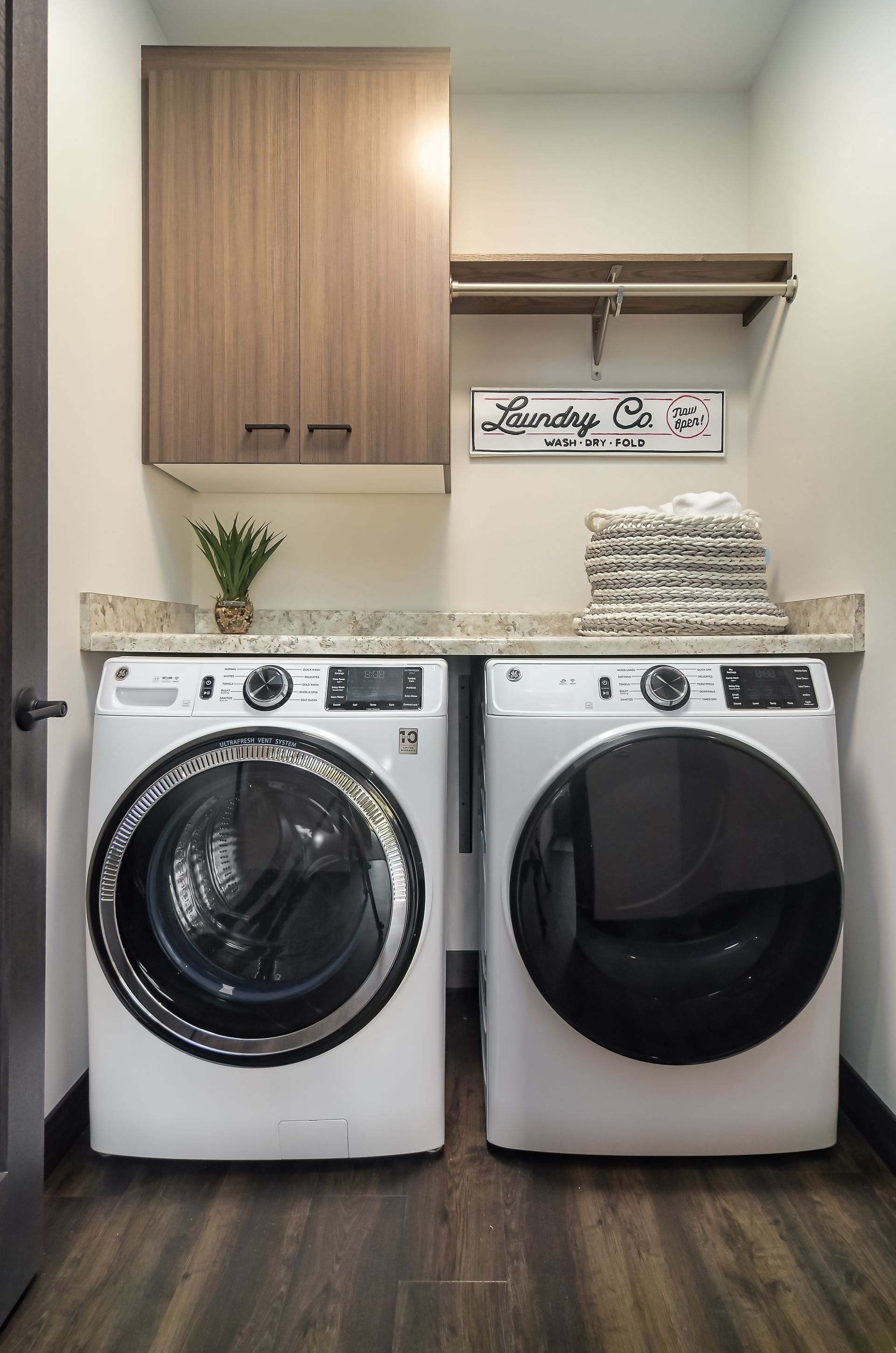 Laundry room with a washer and dryer, countertop, cabinets, and shelving.