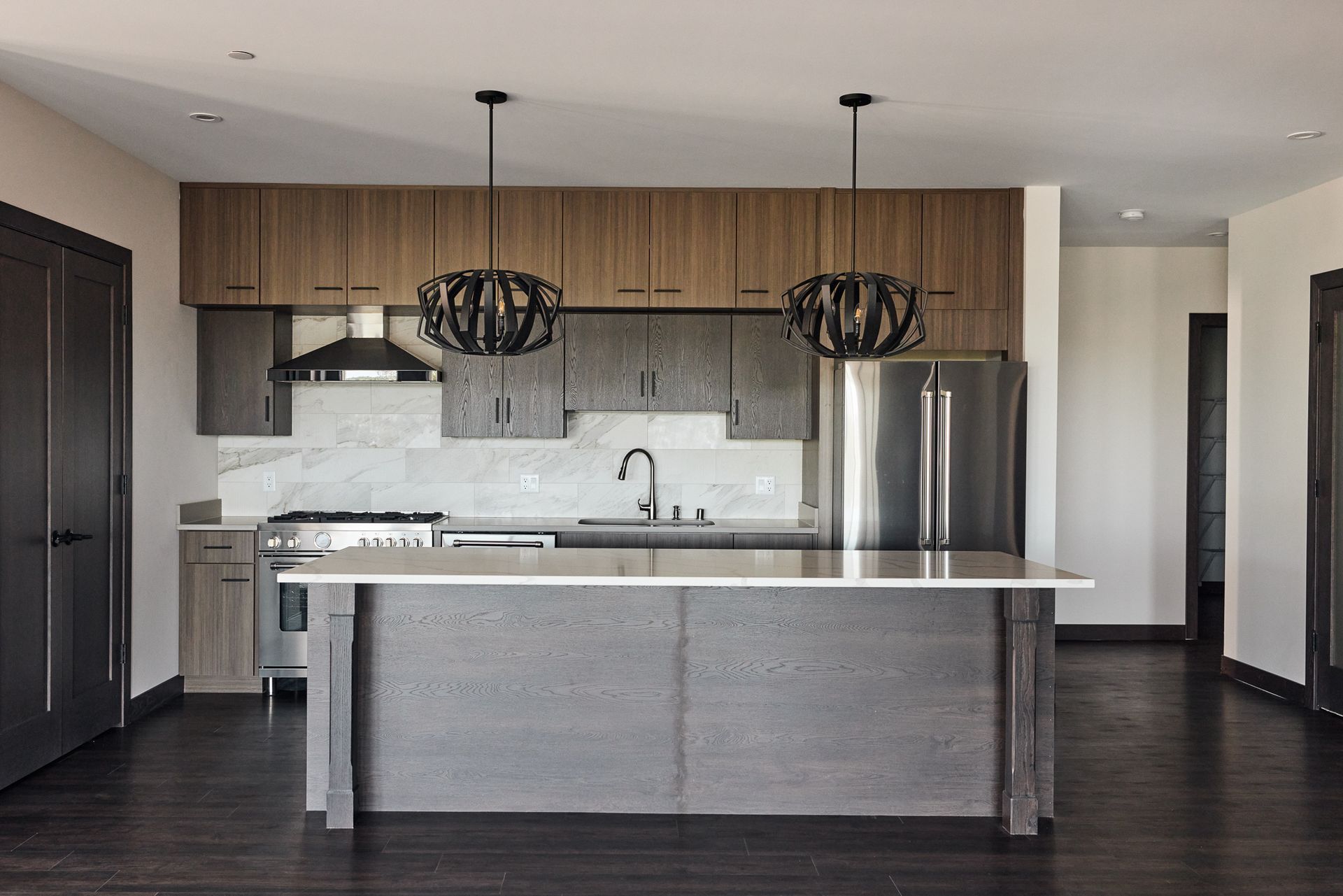Modern kitchen with wood cabinets, stainless steel appliances, and dark island.