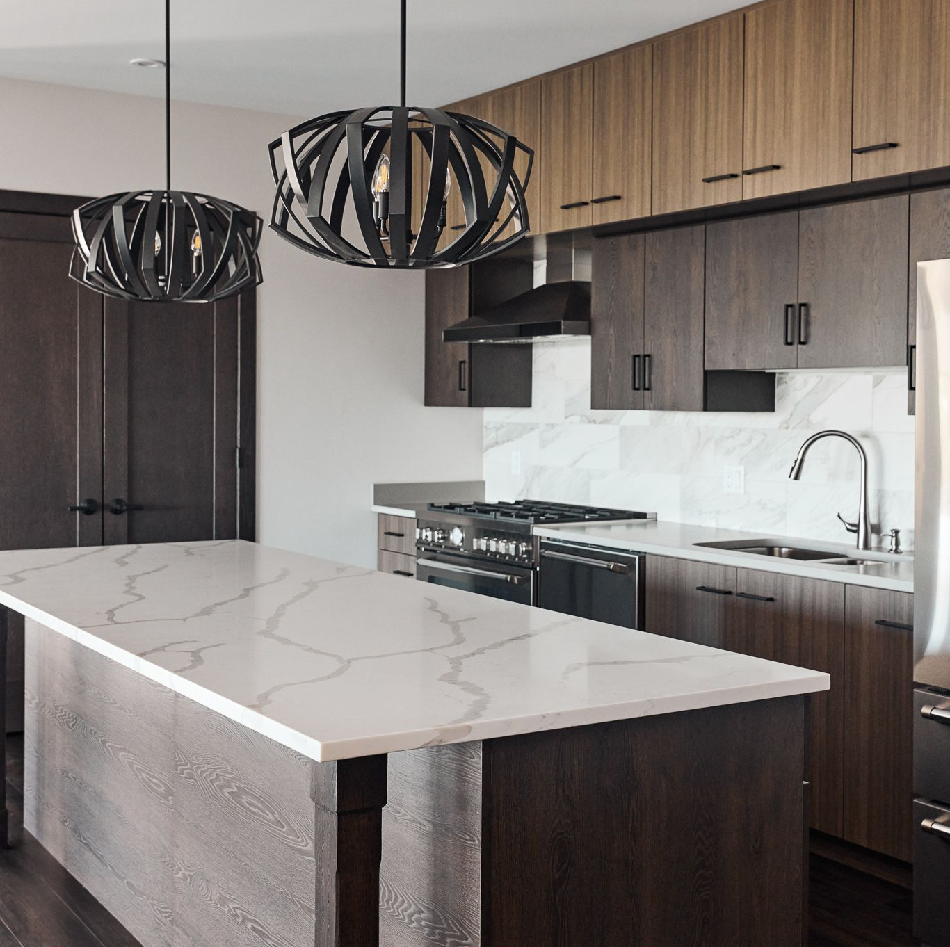 Modern kitchen with dark cabinetry, white countertop, and pendant lights.