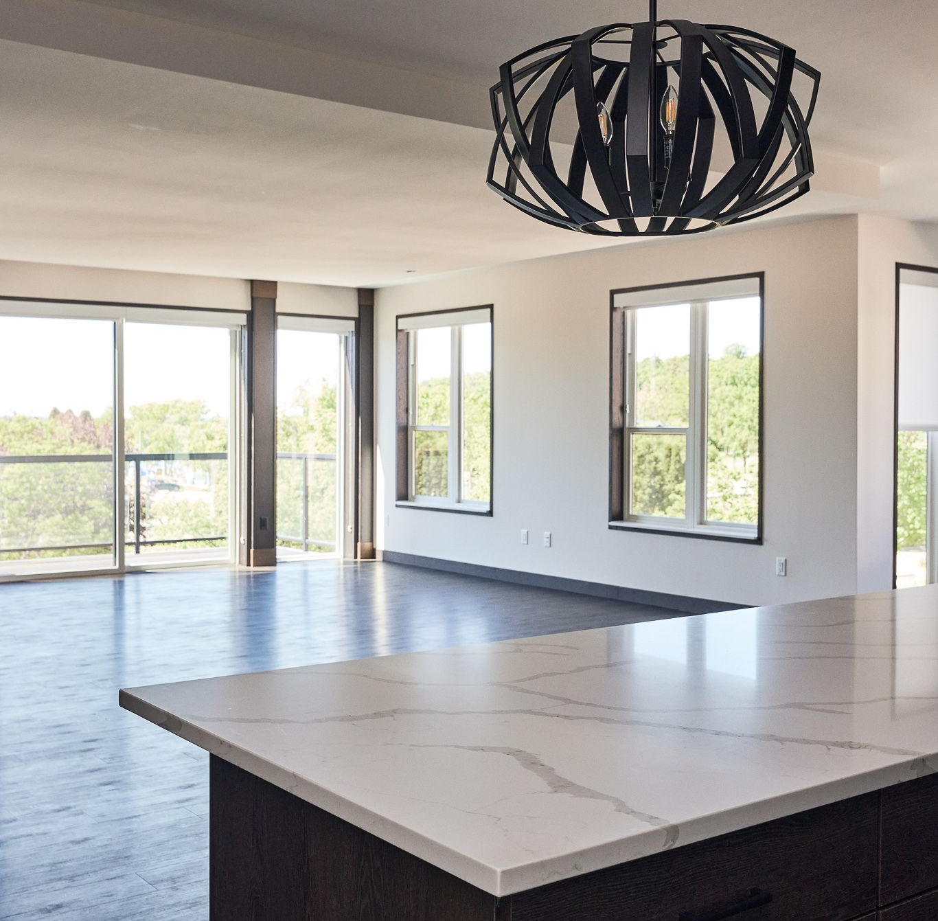 Modern kitchen interior with white countertops, wooden cabinets, and large windows.