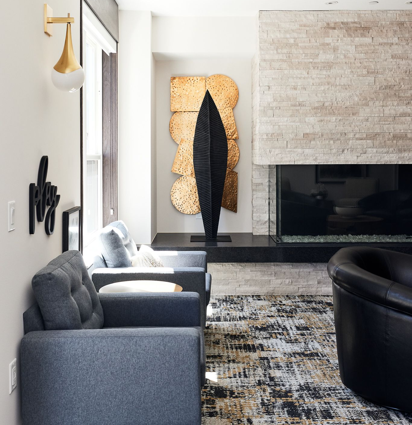 Living room with modern art, gray couches, fireplace, and patterned rug.