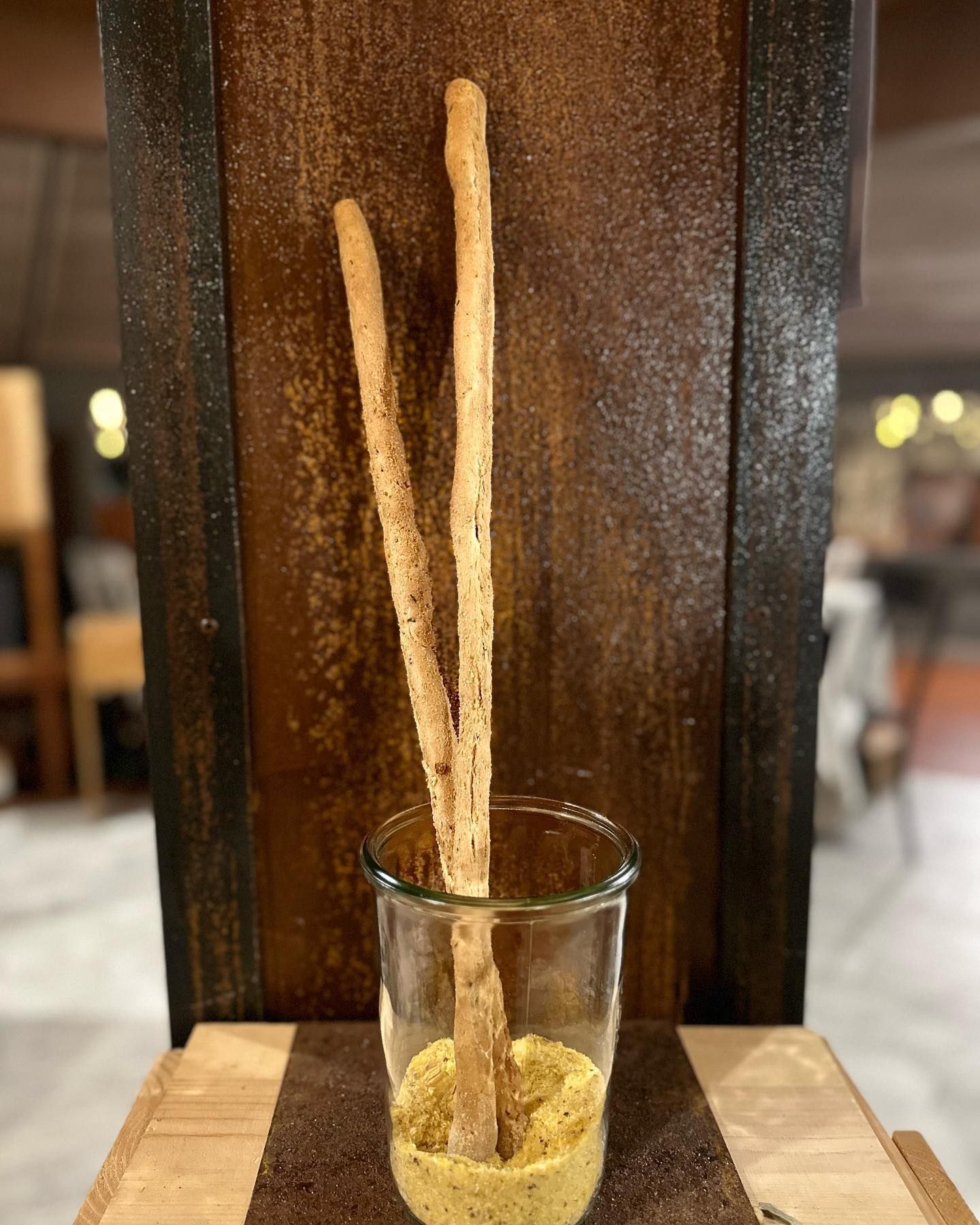 Un bicchiere pieno di grissini e senape su un tavolo.