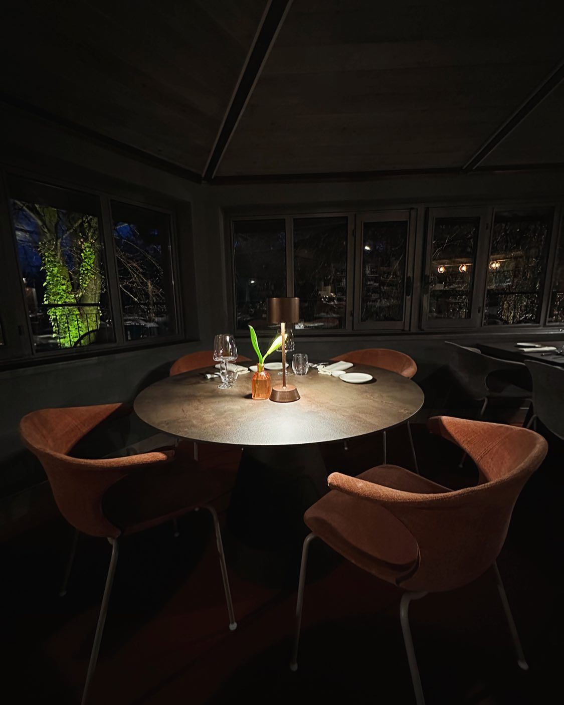 Una stanza buia con un tavolo rotondo e sedie