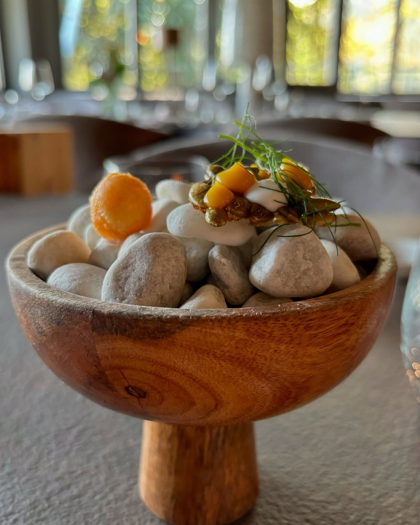 Una ciotola di legno piena di pietre e verdure su un tavolo.