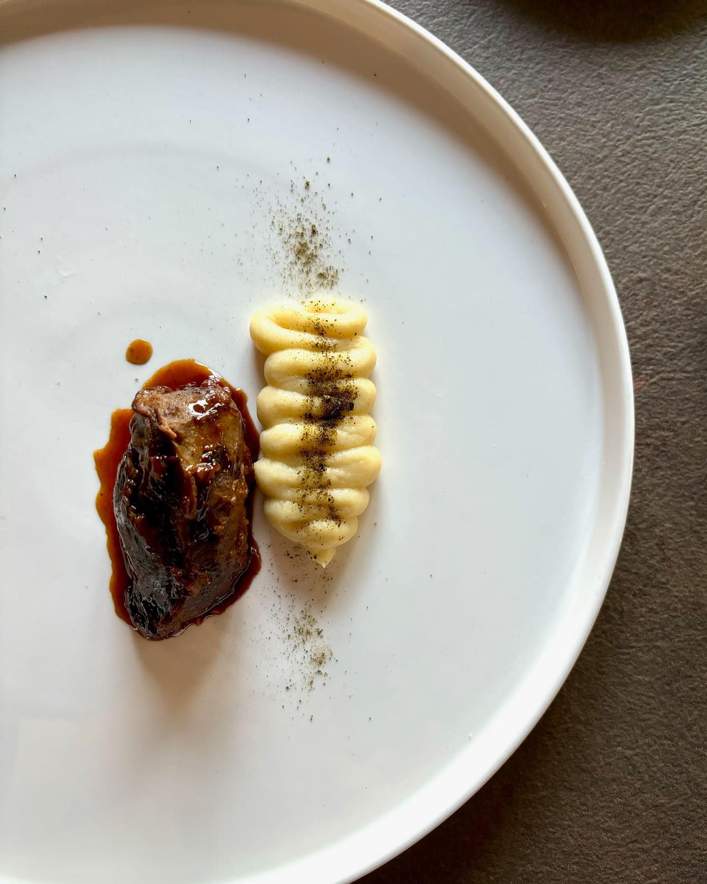 Un piatto bianco con sopra un pezzo di carne e purè di patate