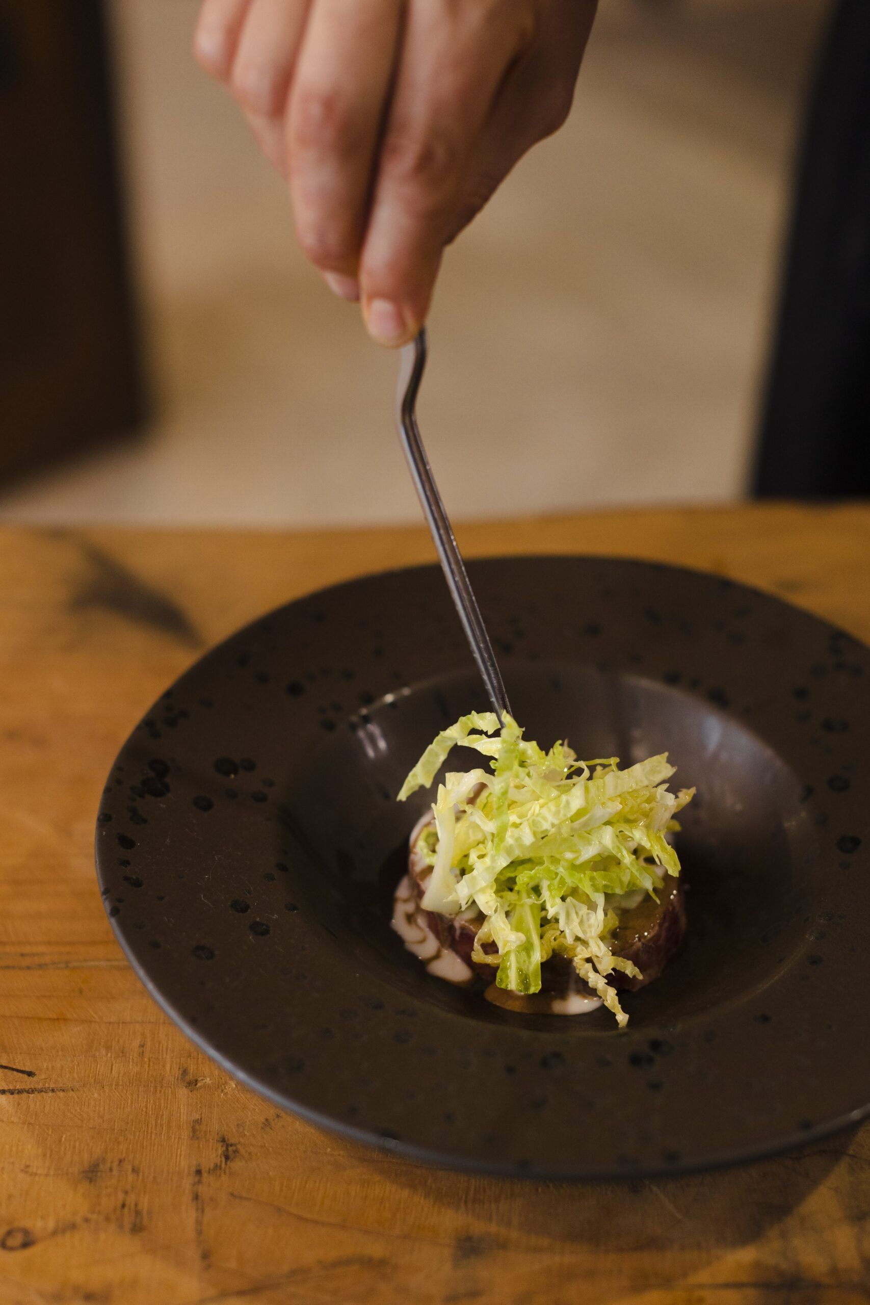 Una persona mette la lattuga su un piatto con una forchetta.