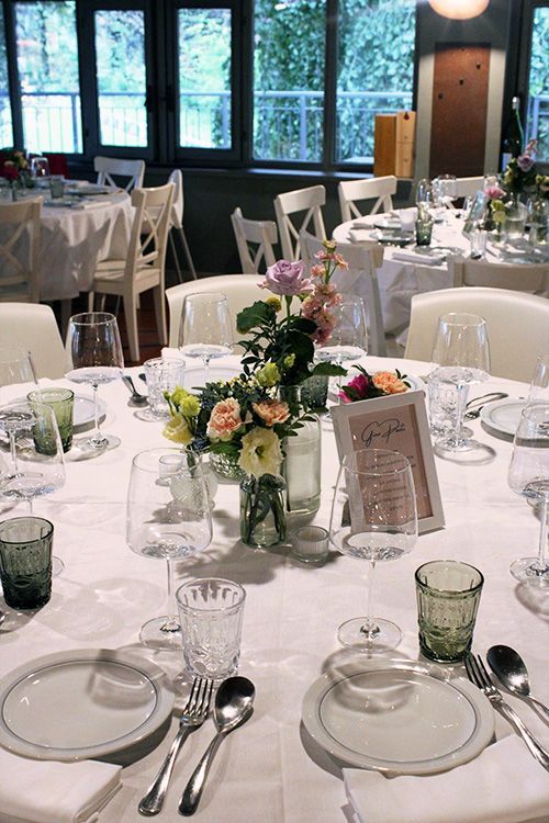 Un tavolo apparecchiato per un ricevimento di nozze con piatti, bicchieri e fiori.